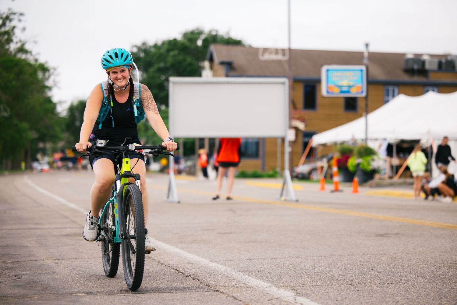 Cyclist riding a green bicycle on a paved road during an outdoor event.
