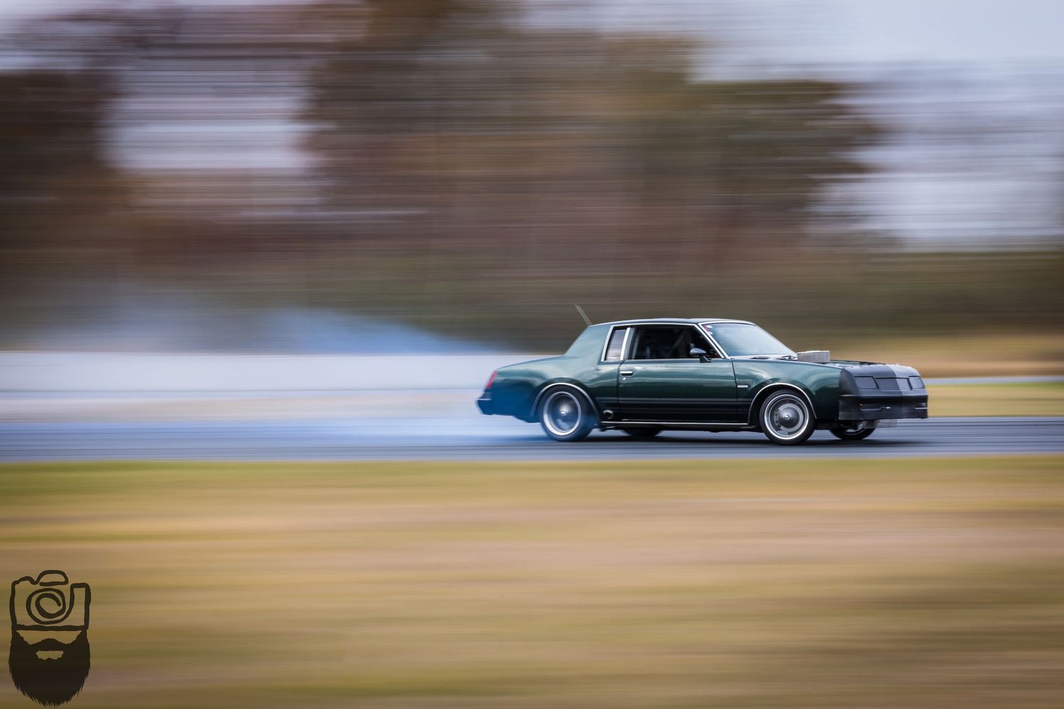 Classic car racing on track with motion blur effect showing speed and movement.