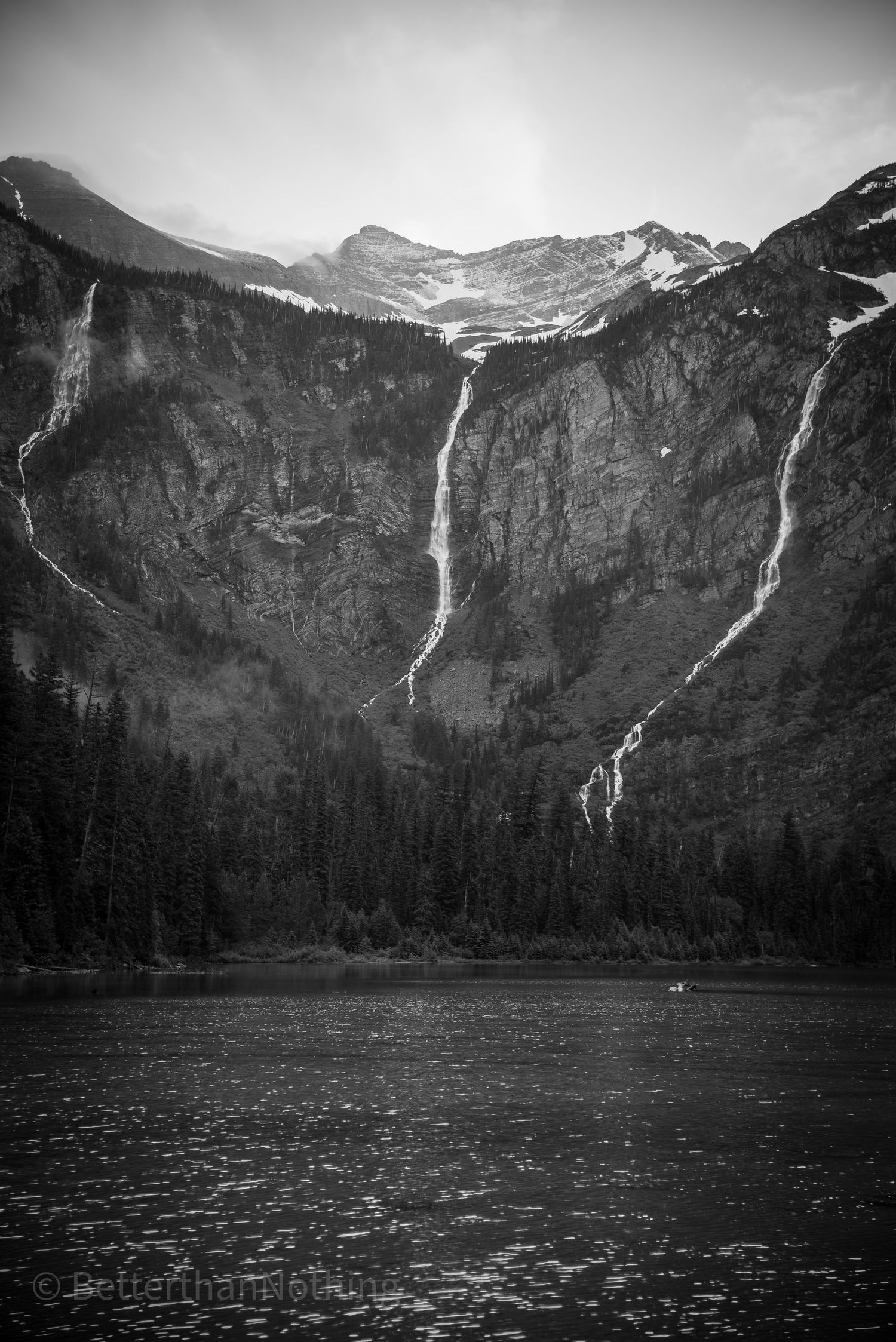 Black and white landscape of dramatic mountain waterfalls cascading down steep cliffs.