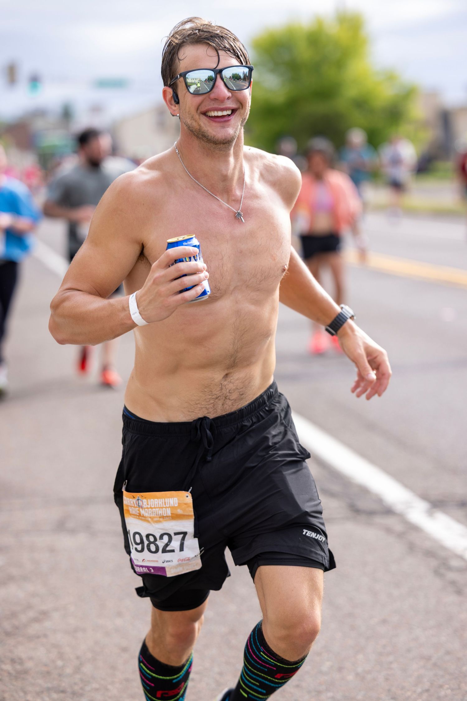 Shirtless runner competing in marathon wearing race bib number.
