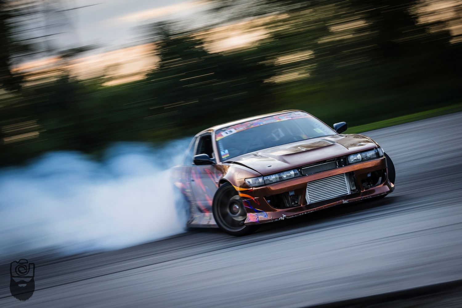 Racing car creating smoke while drifting on track surface.