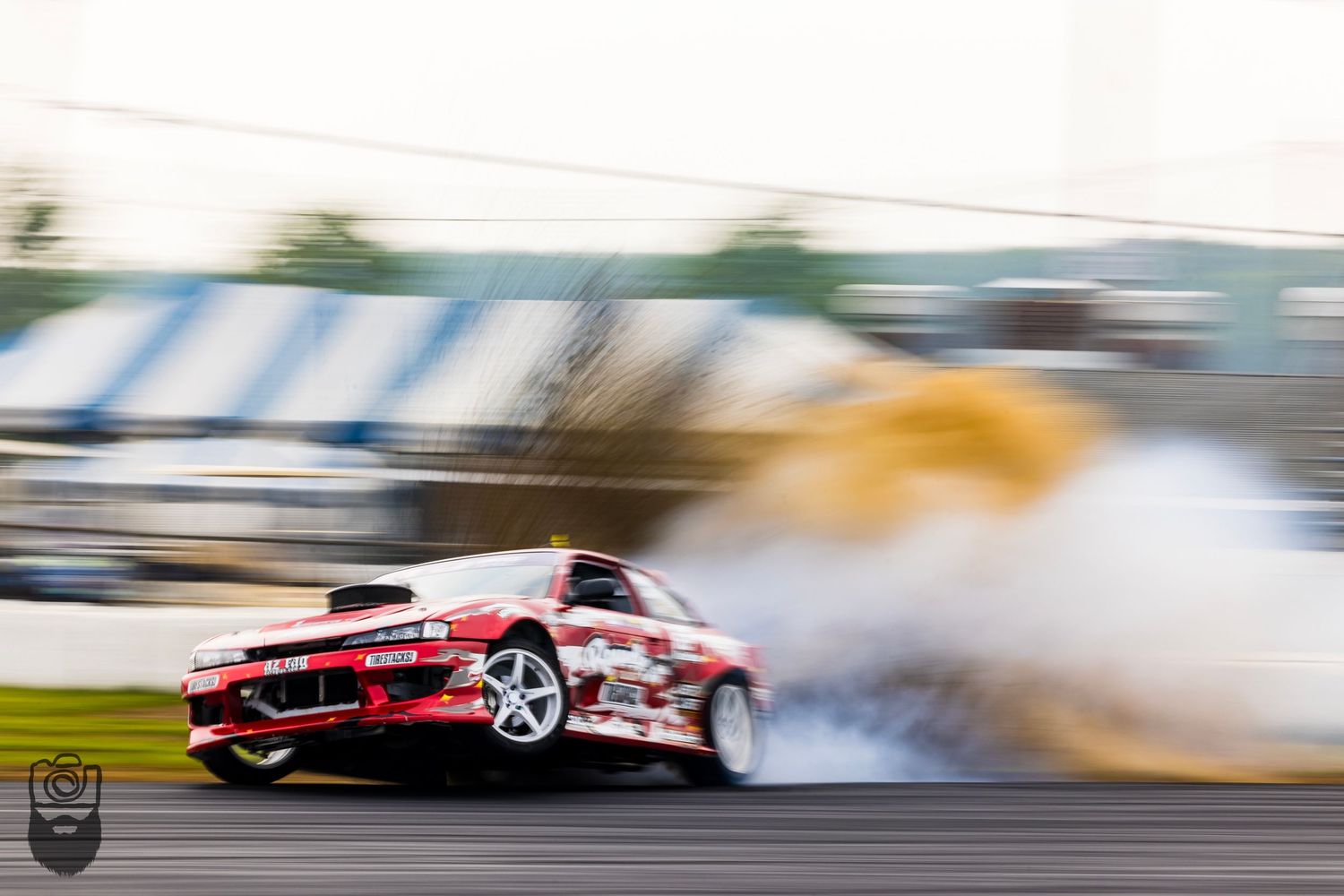 Modified BMW race car drifting with tire smoke on track.