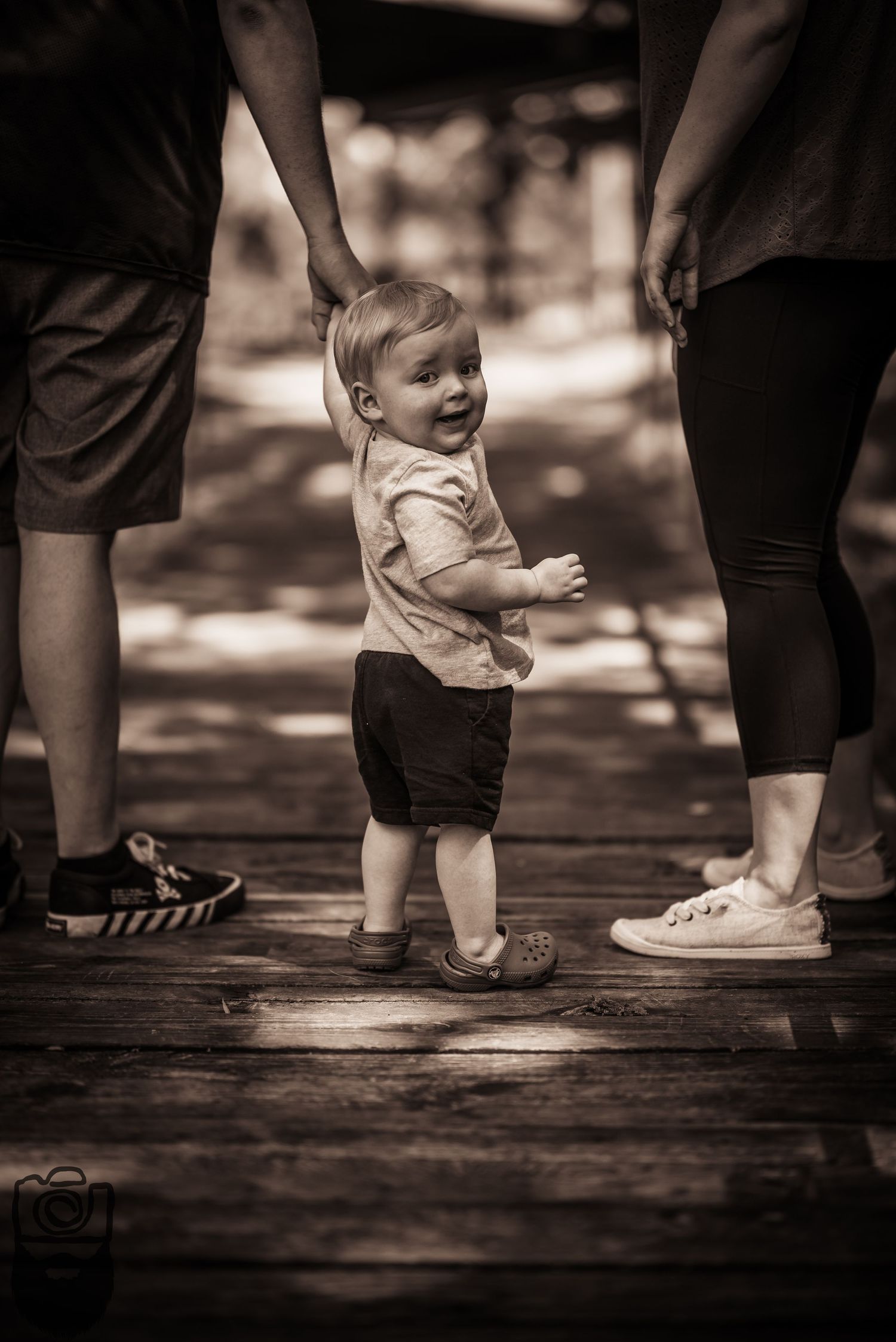 Close-up view of feet walking on a wooden deck, showing adults and a small child.