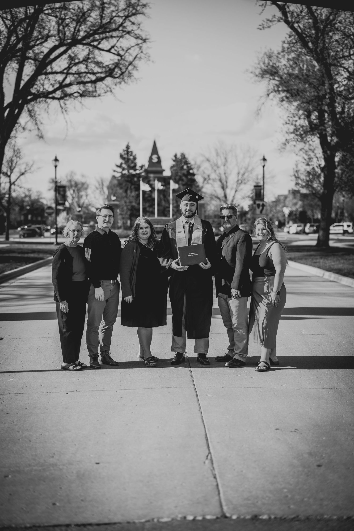 Black and white photo of graduates and family members standing together on a sidewalk.
