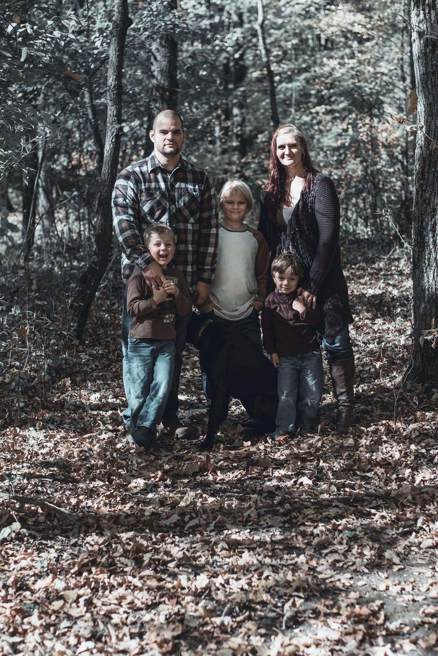 Group photo of family members standing together in autumn woods.