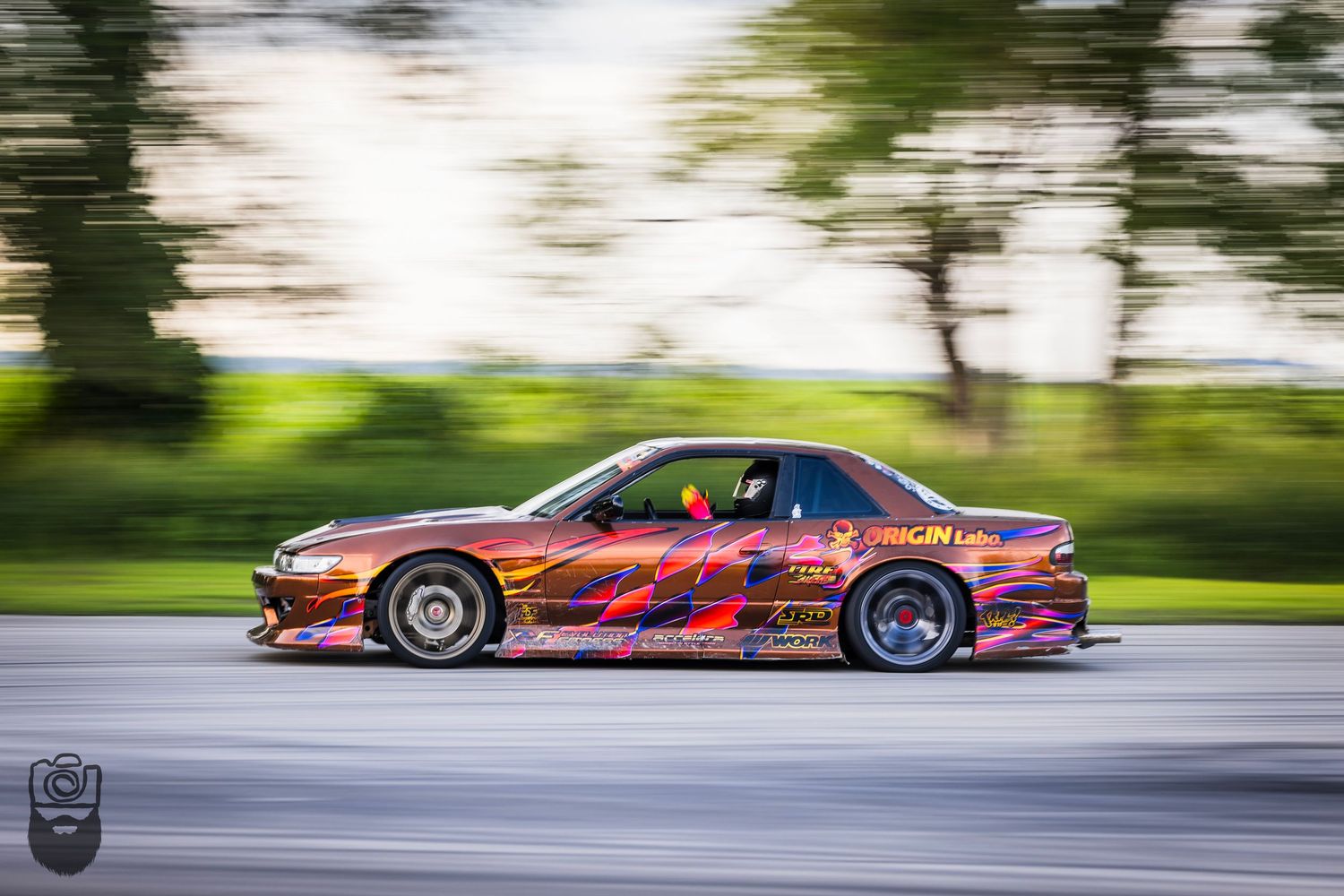 Custom painted race car performing a drift on asphalt track.