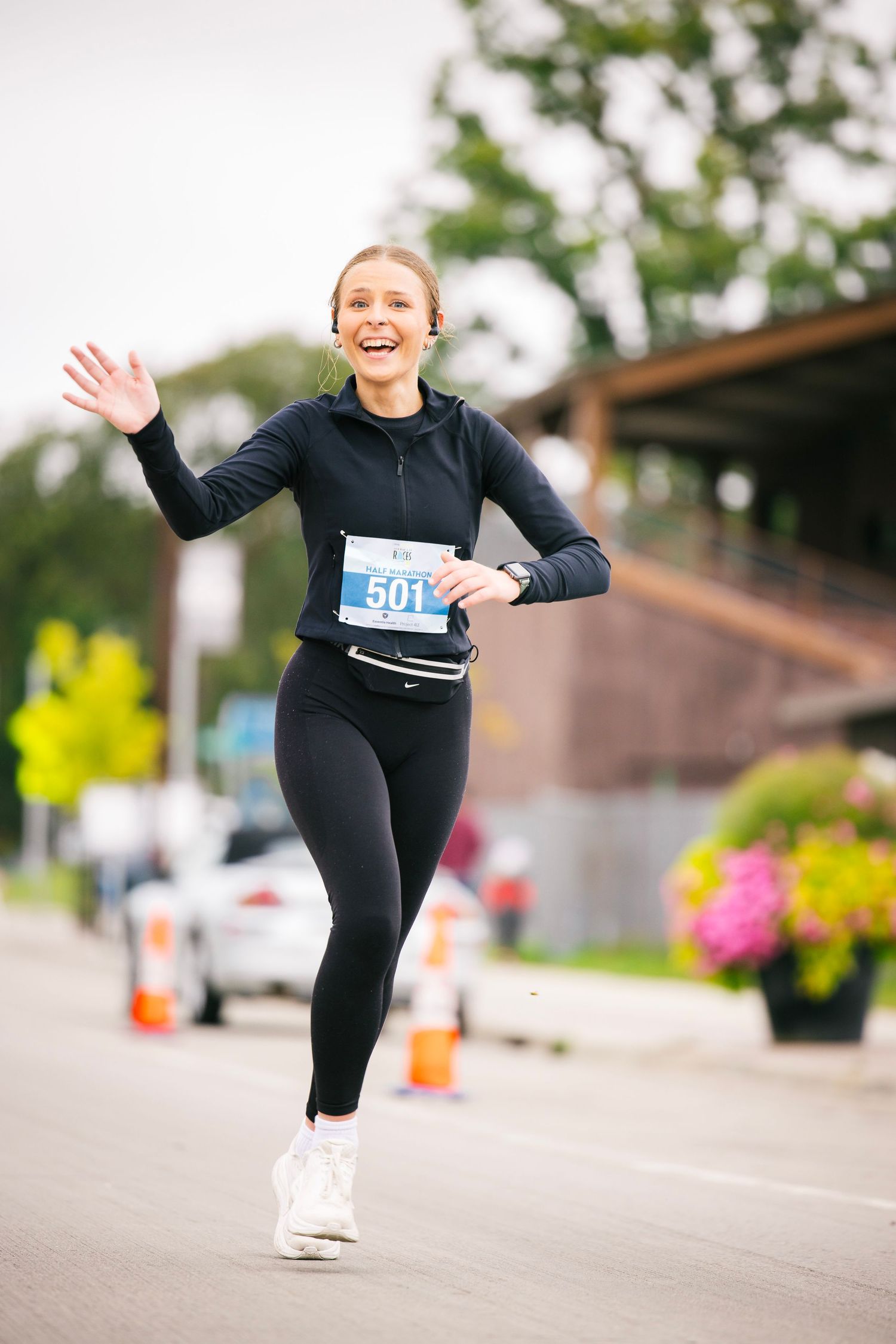 Runner in black athletic wear leaps joyfully during outdoor race competition.