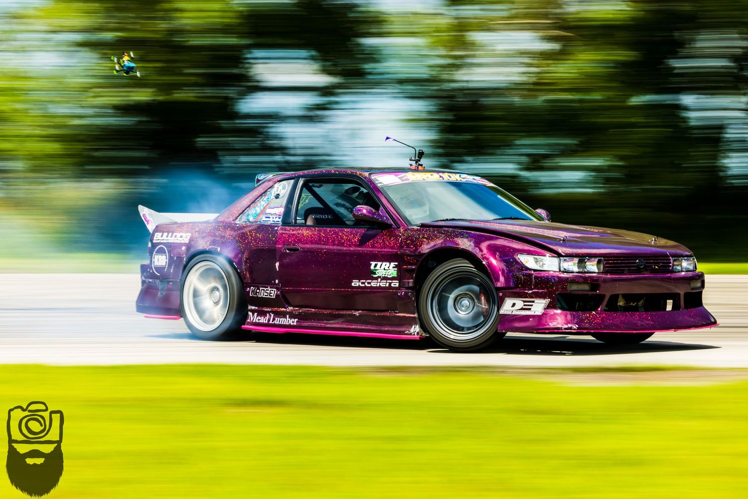 Racing cars create colorful motion blur streaks while drifting on track.