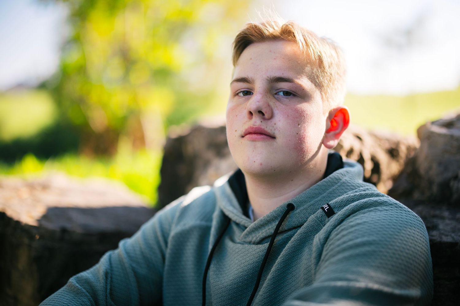 A casual portrait against a natural outdoor background with soft lighting and bokeh effects.