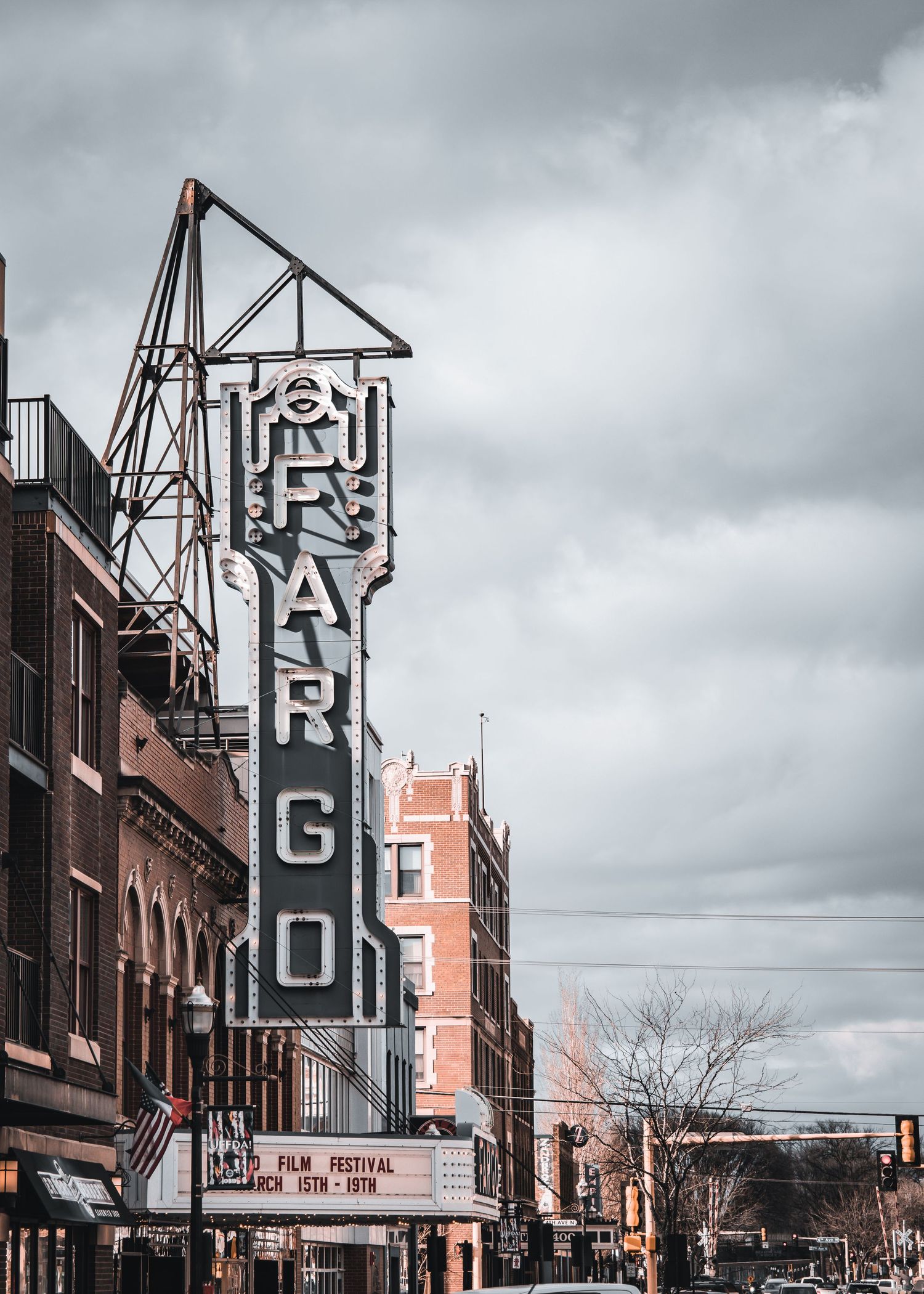 Vintage theater marquee sign on brick building under cloudy sky.