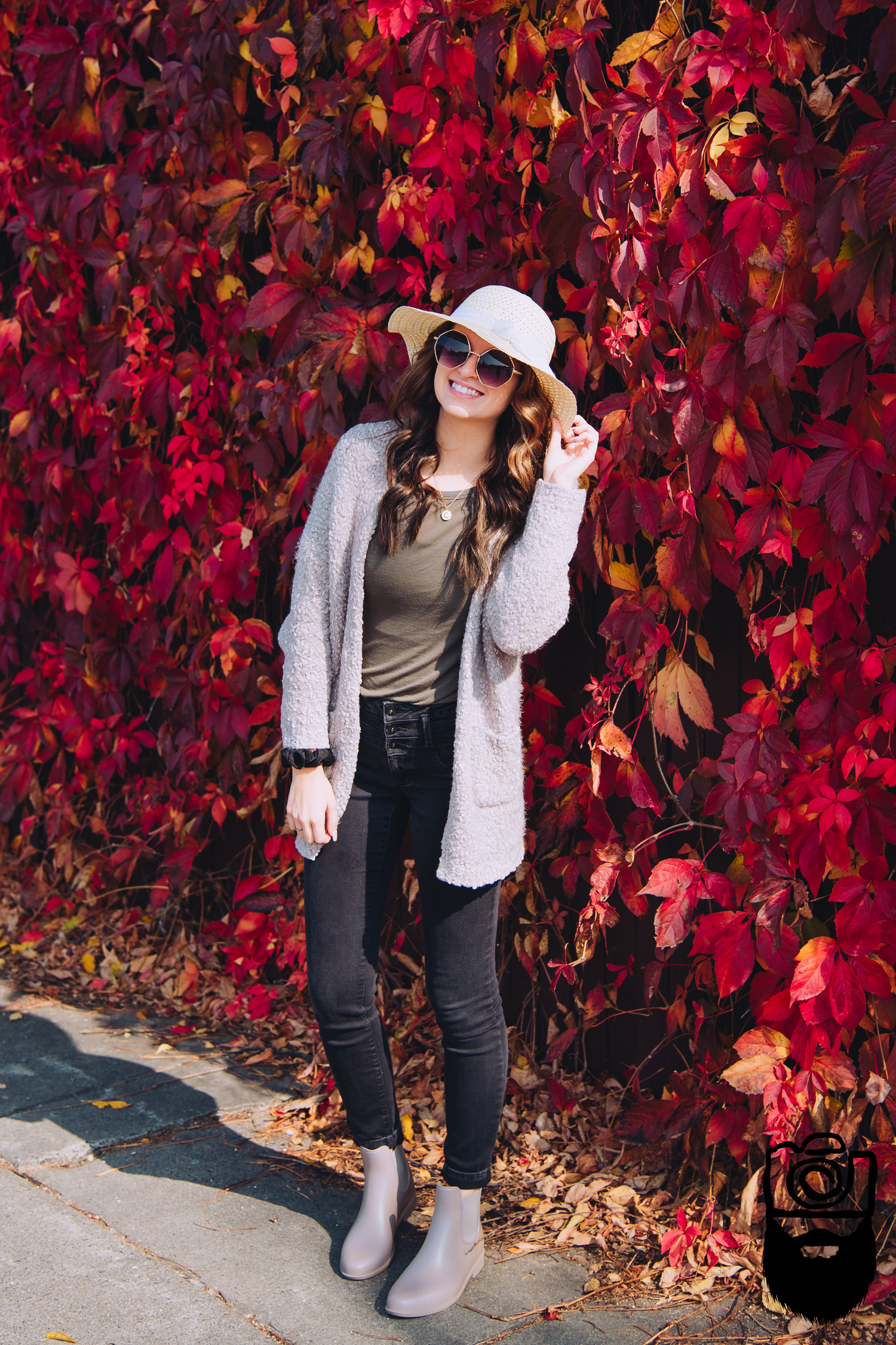 Fall fashion outfit against vibrant red autumn leaves background.