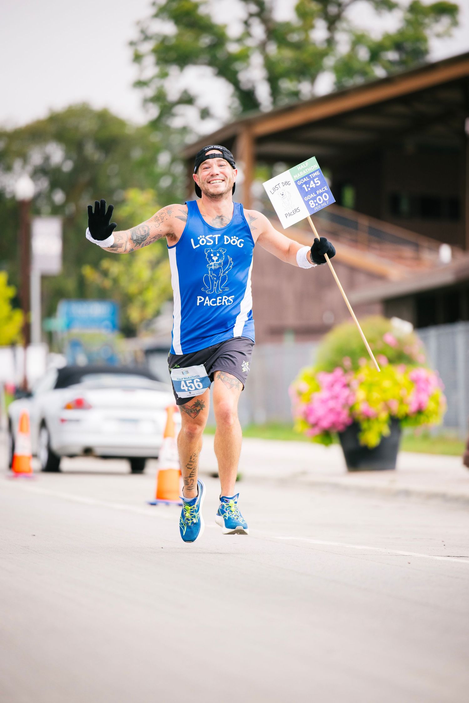 Runner in blue shirt waves flags while participating in outdoor street race.