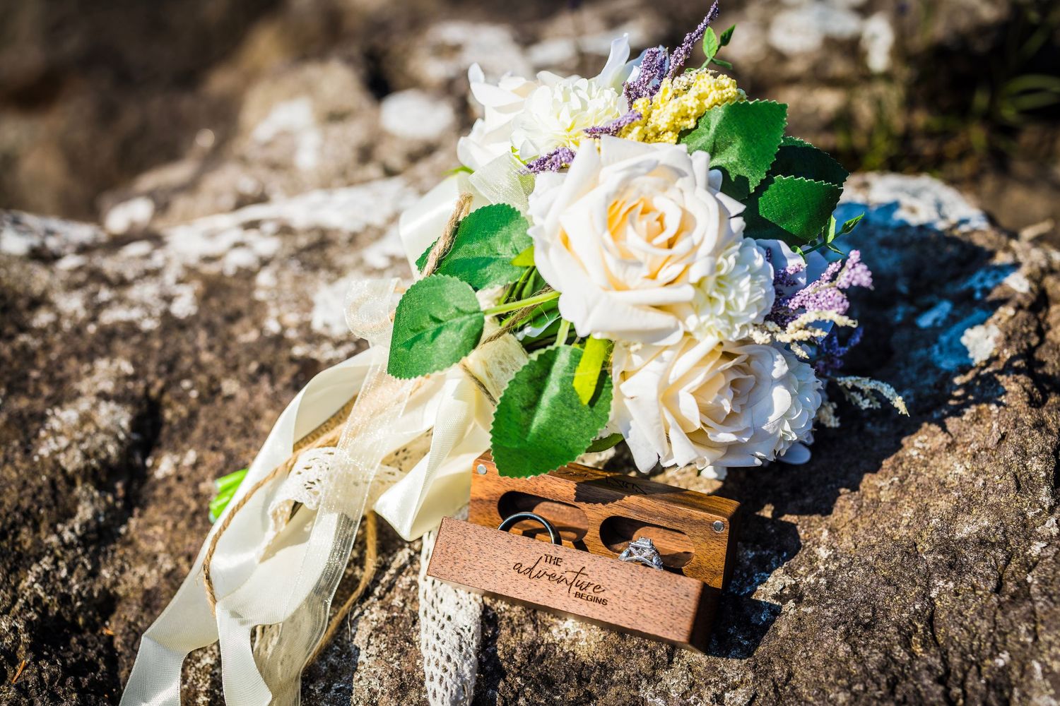 Wedding decorations featuring cream roses and blue flowers arranged on natural stone.