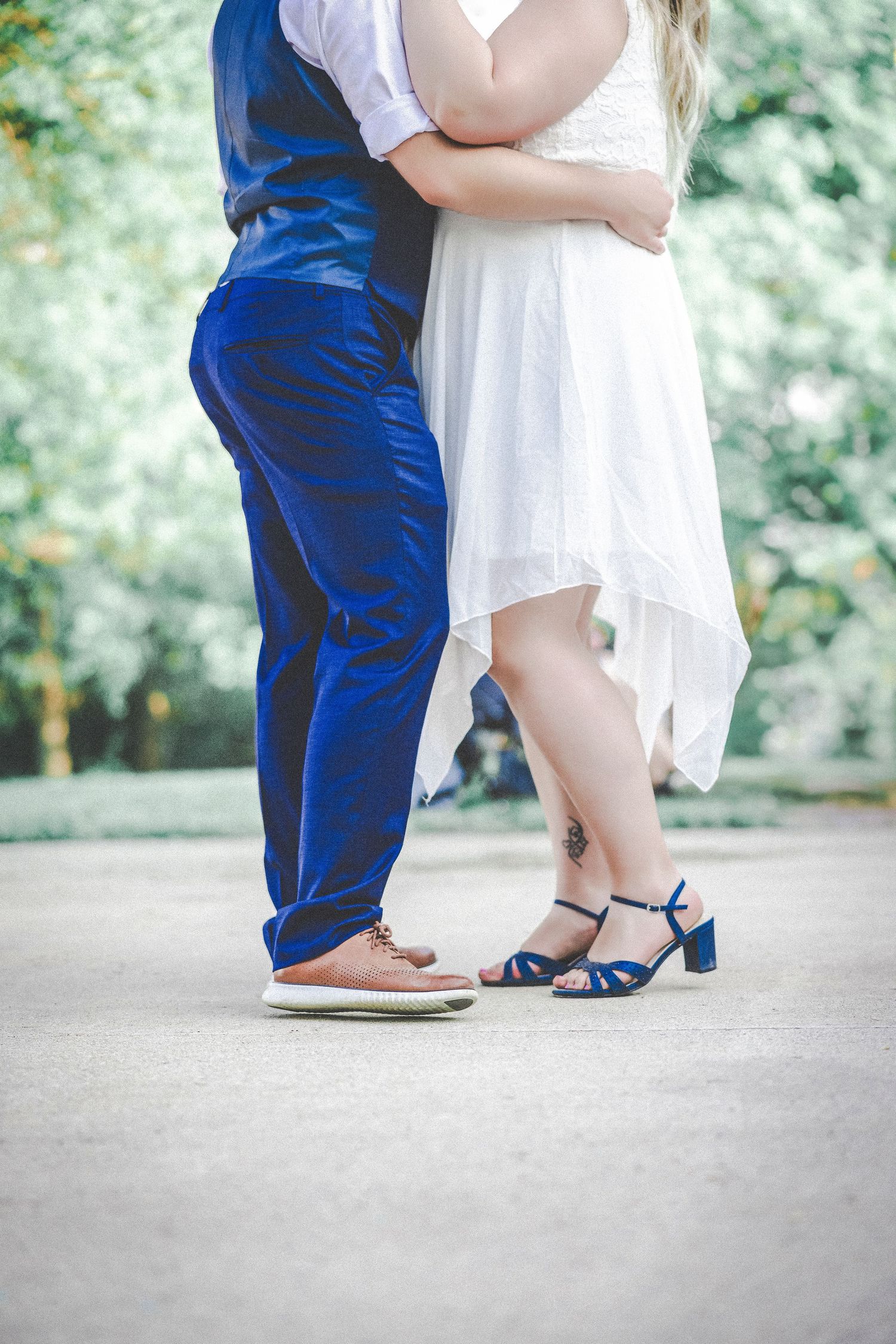 Close-up of wedding attire showing blue suit pants and white dress with blue heels.