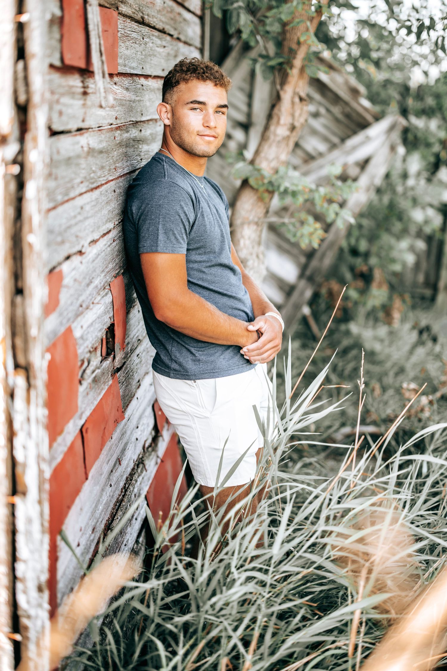 Athletic photo shoot with person posing against weathered red and white barn siding.