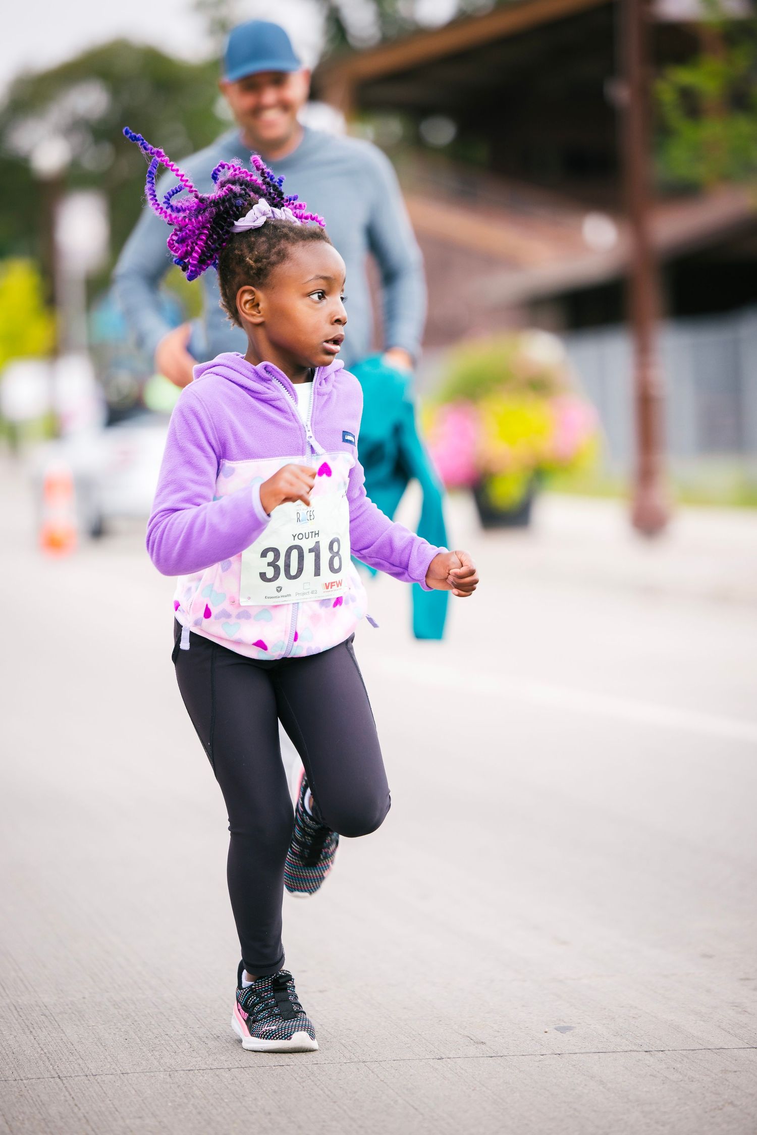 Young participant in purple outfit running during children's race event.