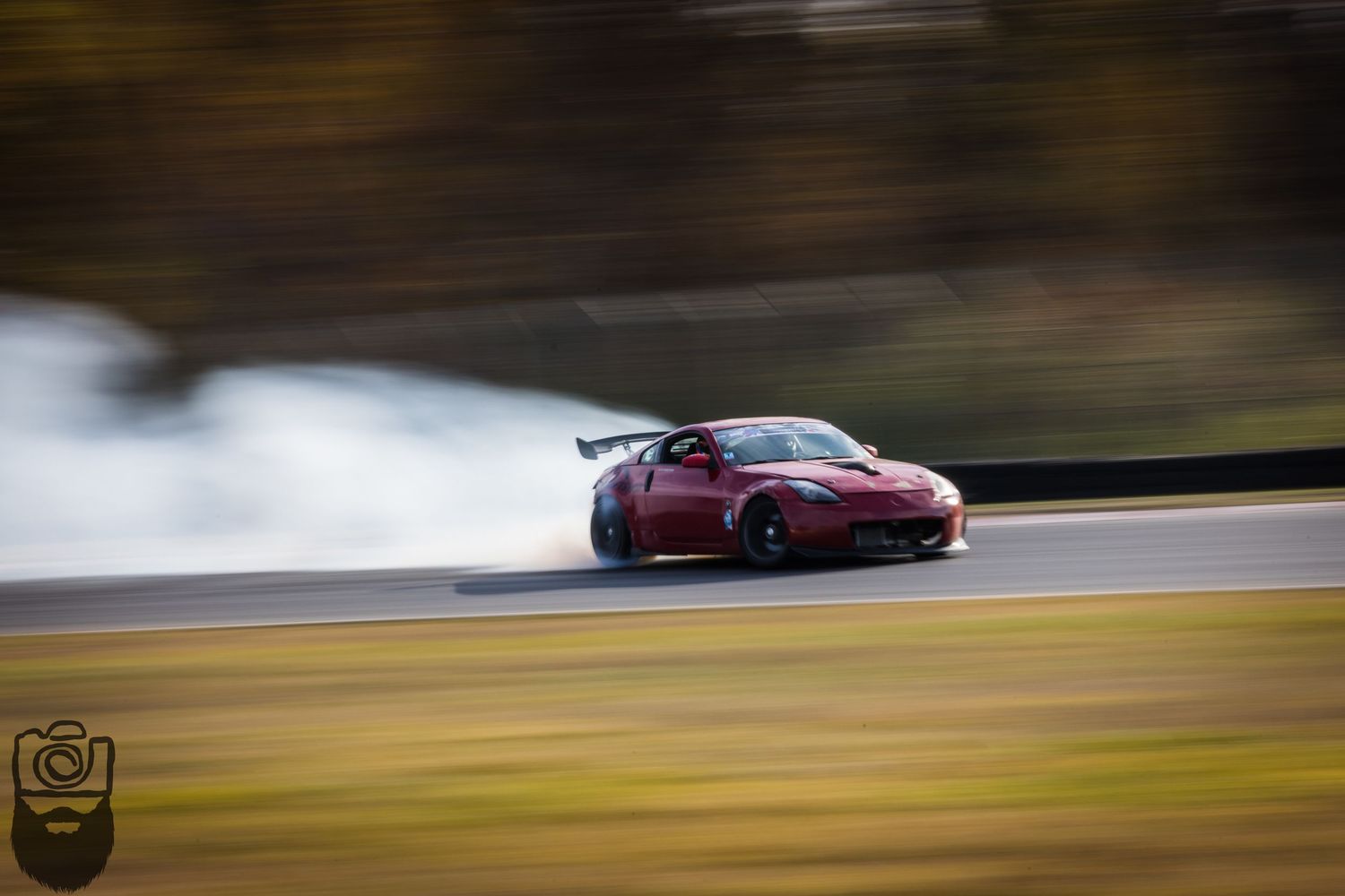 Red sports car drifting on racetrack with motion blur effect.