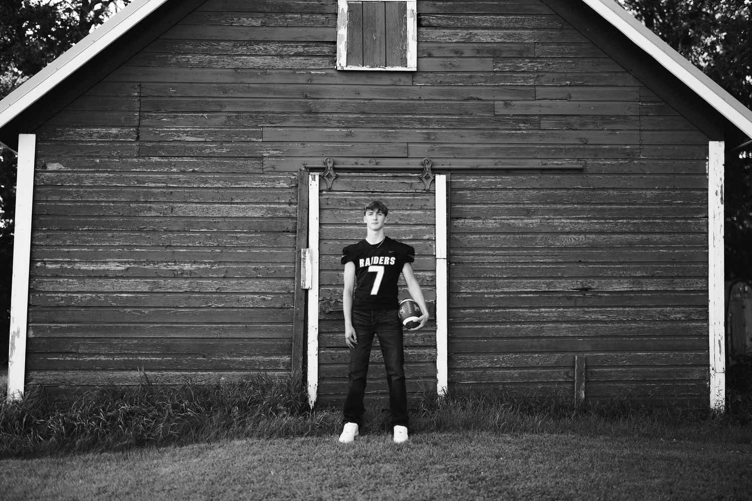 Silhouette stands against a rustic wooden barn exterior in dramatic black and white.