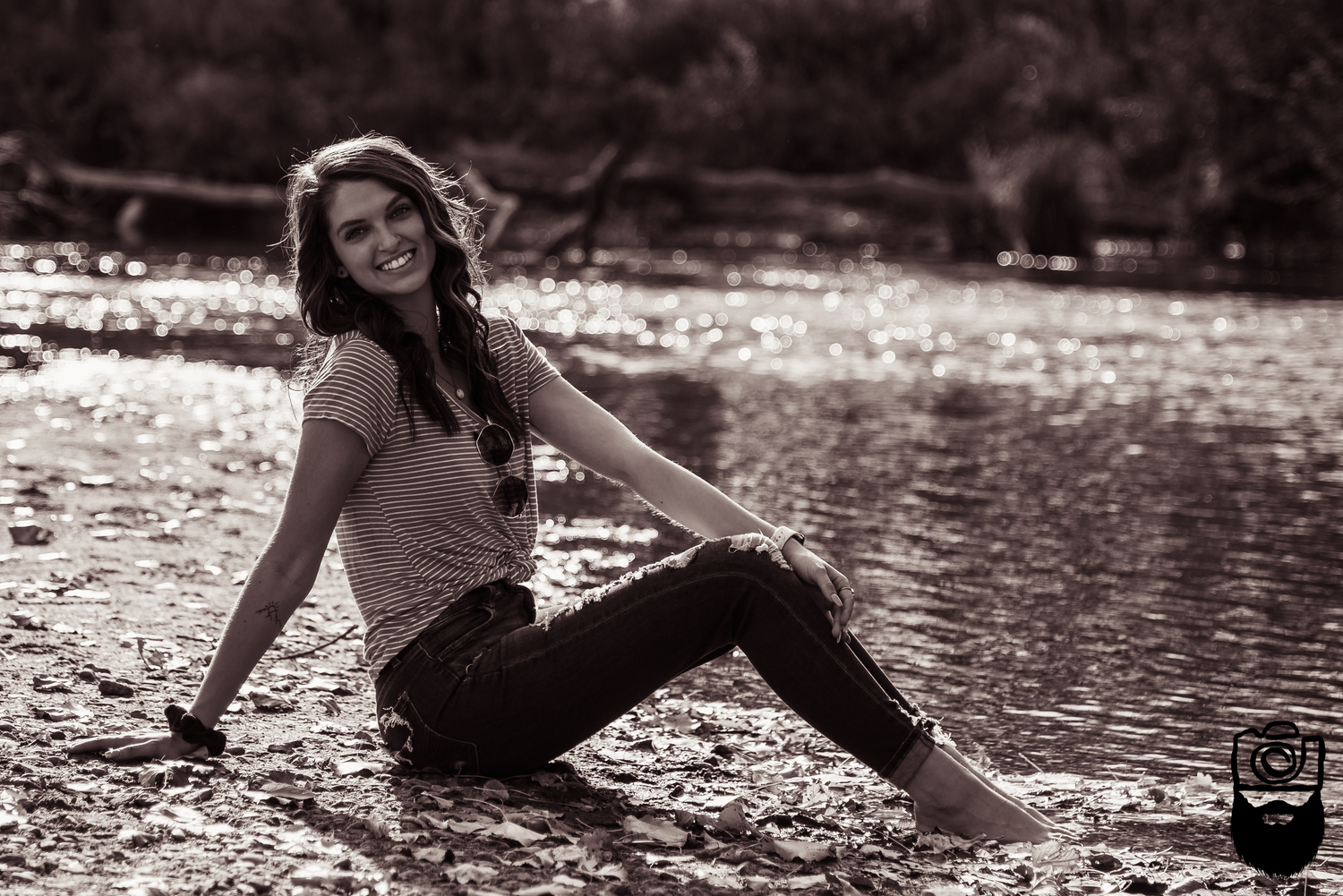 Someone relaxes by a stream wearing casual clothing in a natural outdoor setting.