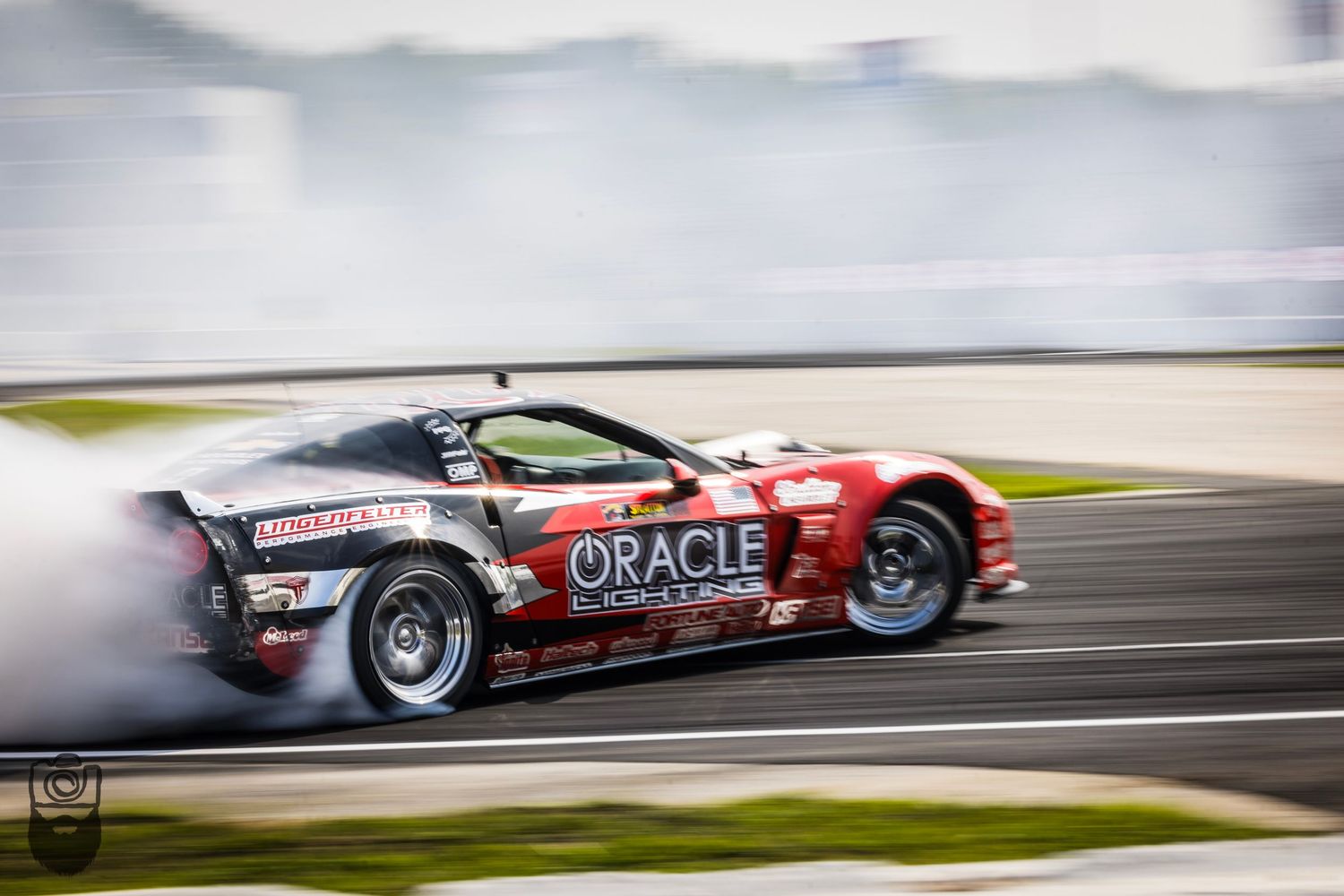 Racing cars drifting on track creating smoke trails during competition.