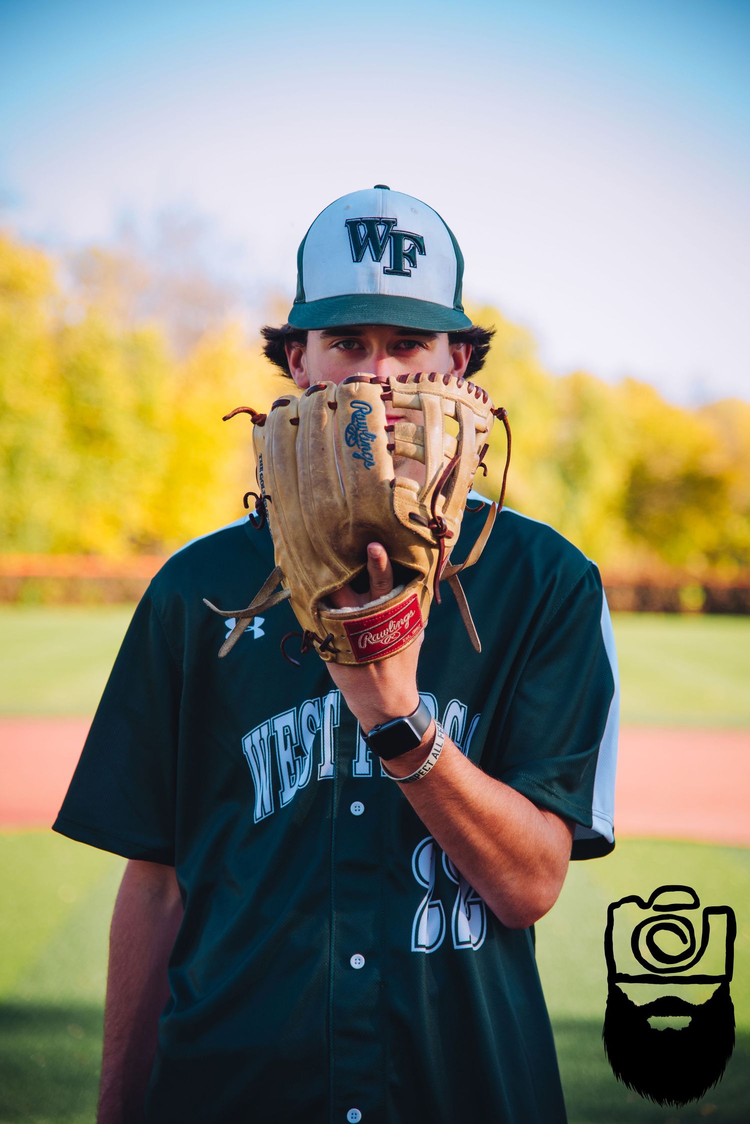 Baseball player in Wake Forest uniform and cap practicing with glove outdoors.