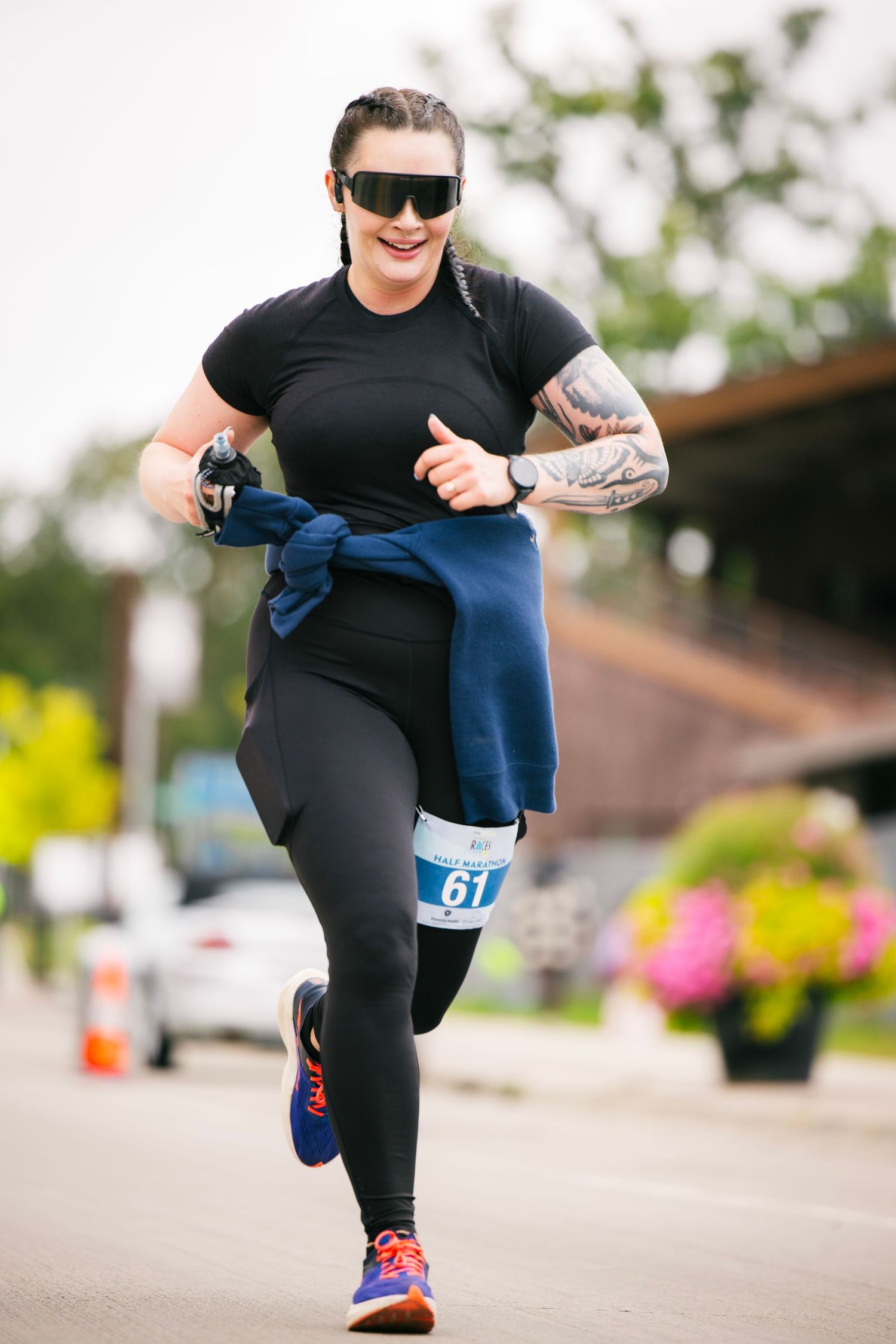 Participant in black athletic wear running on paved course during race event.