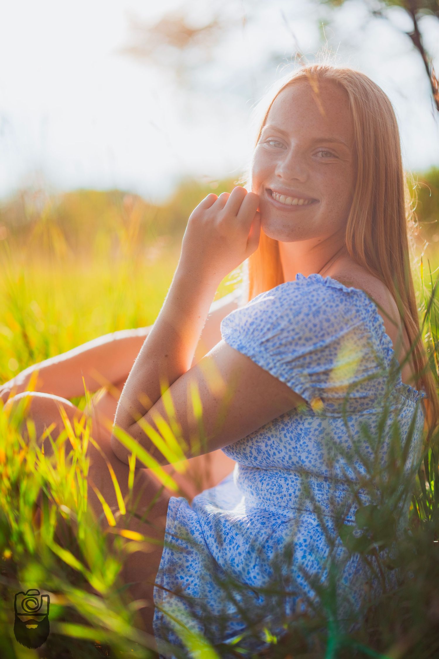 A light and airy summer portrait in a sunlit field with tall grass and golden hour lighting.