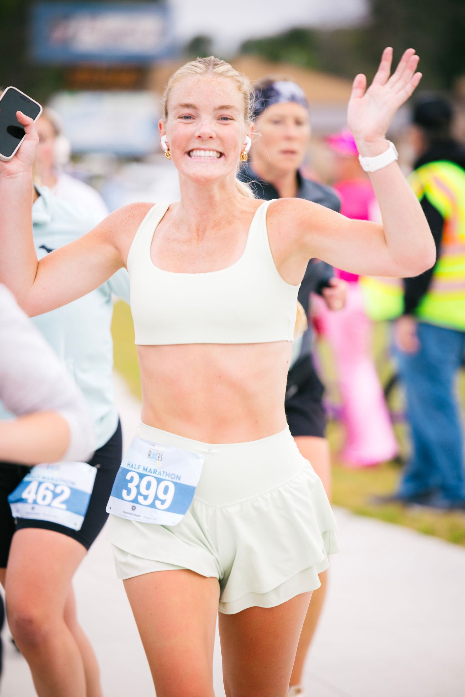 Enthusiastic runners in white athletic wear participate in an outdoor running event with race bibs.