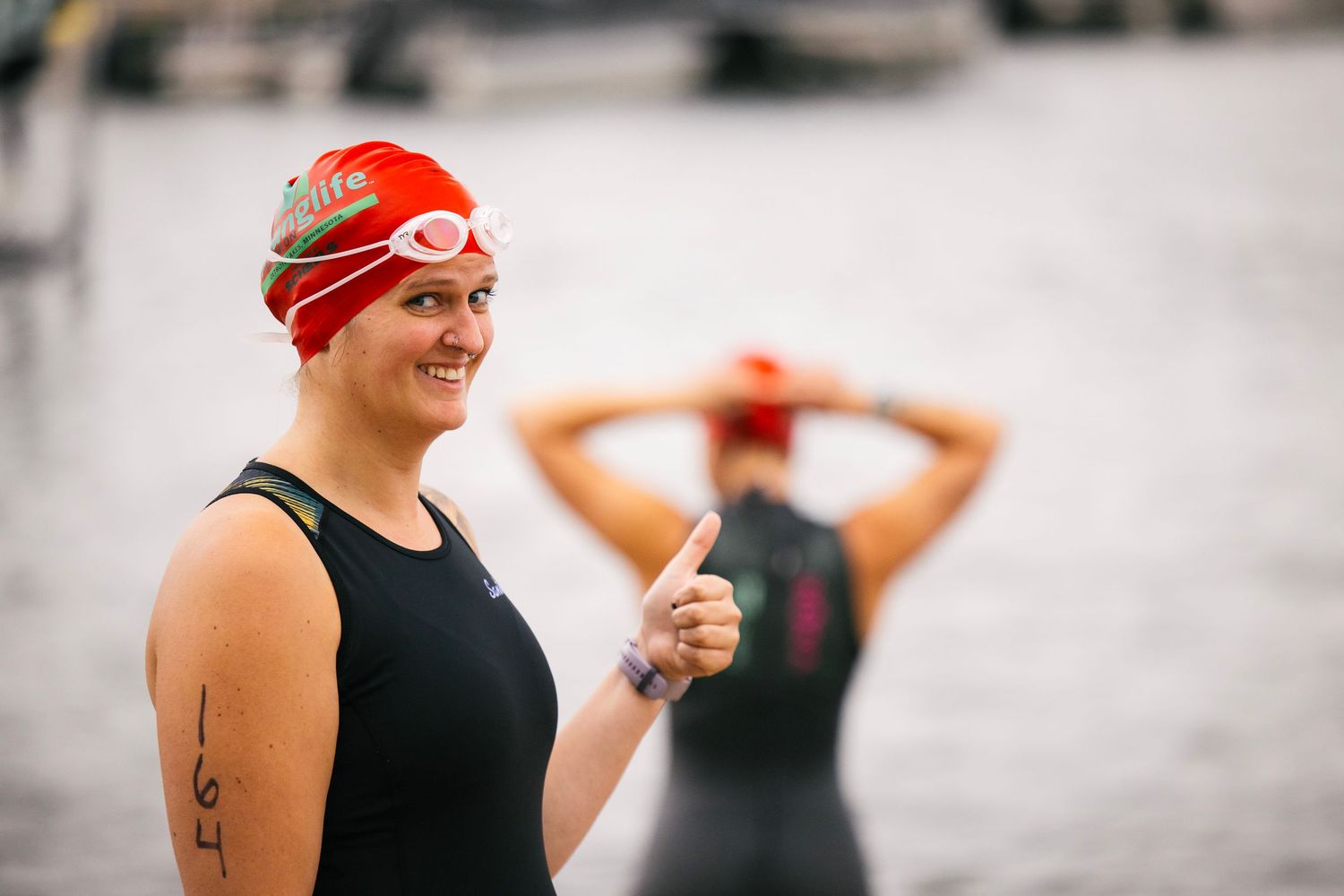 Athletes preparing for a swimming competition wearing swim caps and athletic gear.