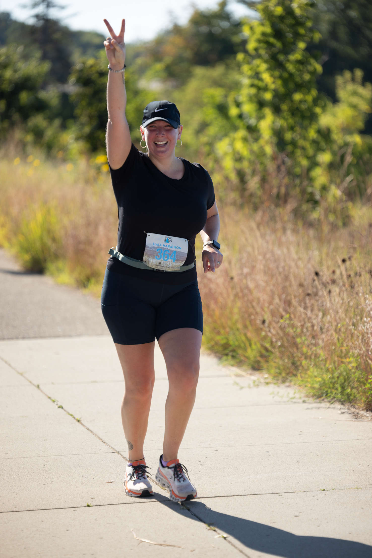 Athletes running on a paved path surrounded by natural vegetation and greenery.