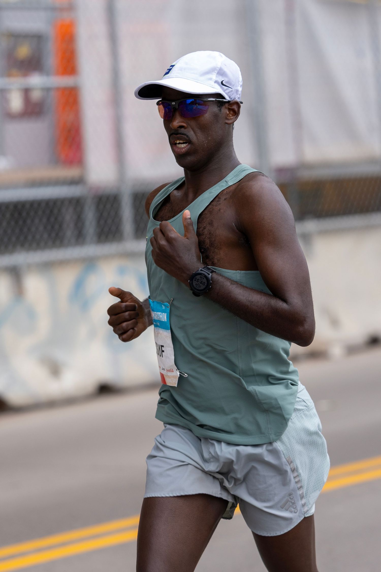 Marathon runners in athletic gear racing through city streets during competition.