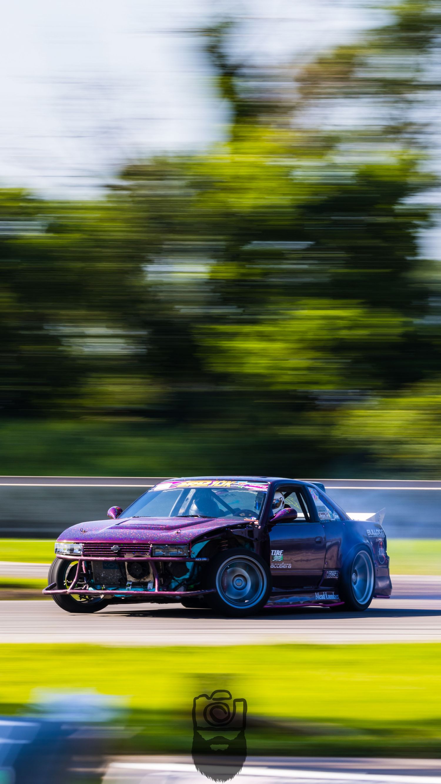 Modified sports cars drift in formation on racing circuit with motion blur effects.