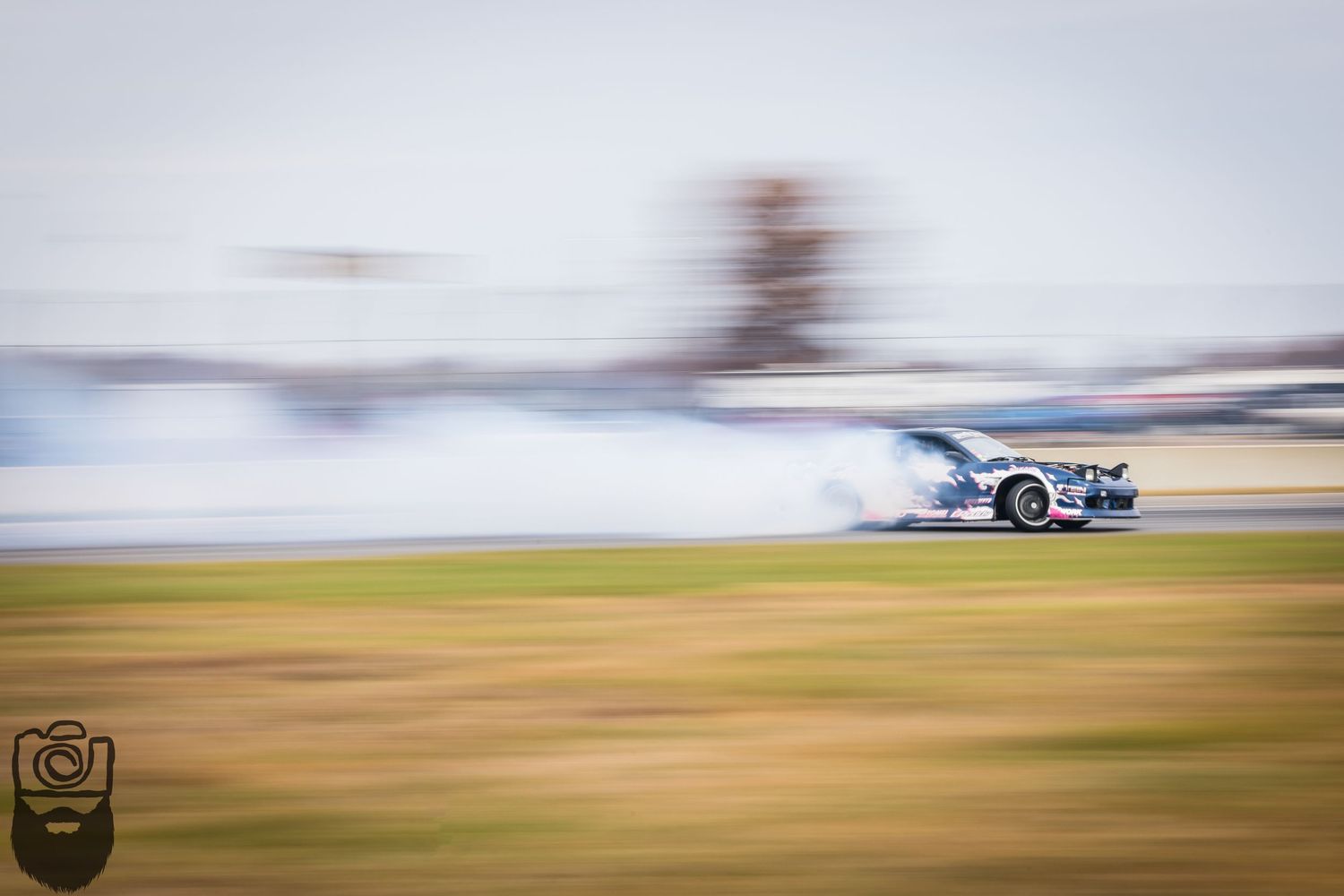 Motion-blurred racing car speeds across track creating dynamic action shot.