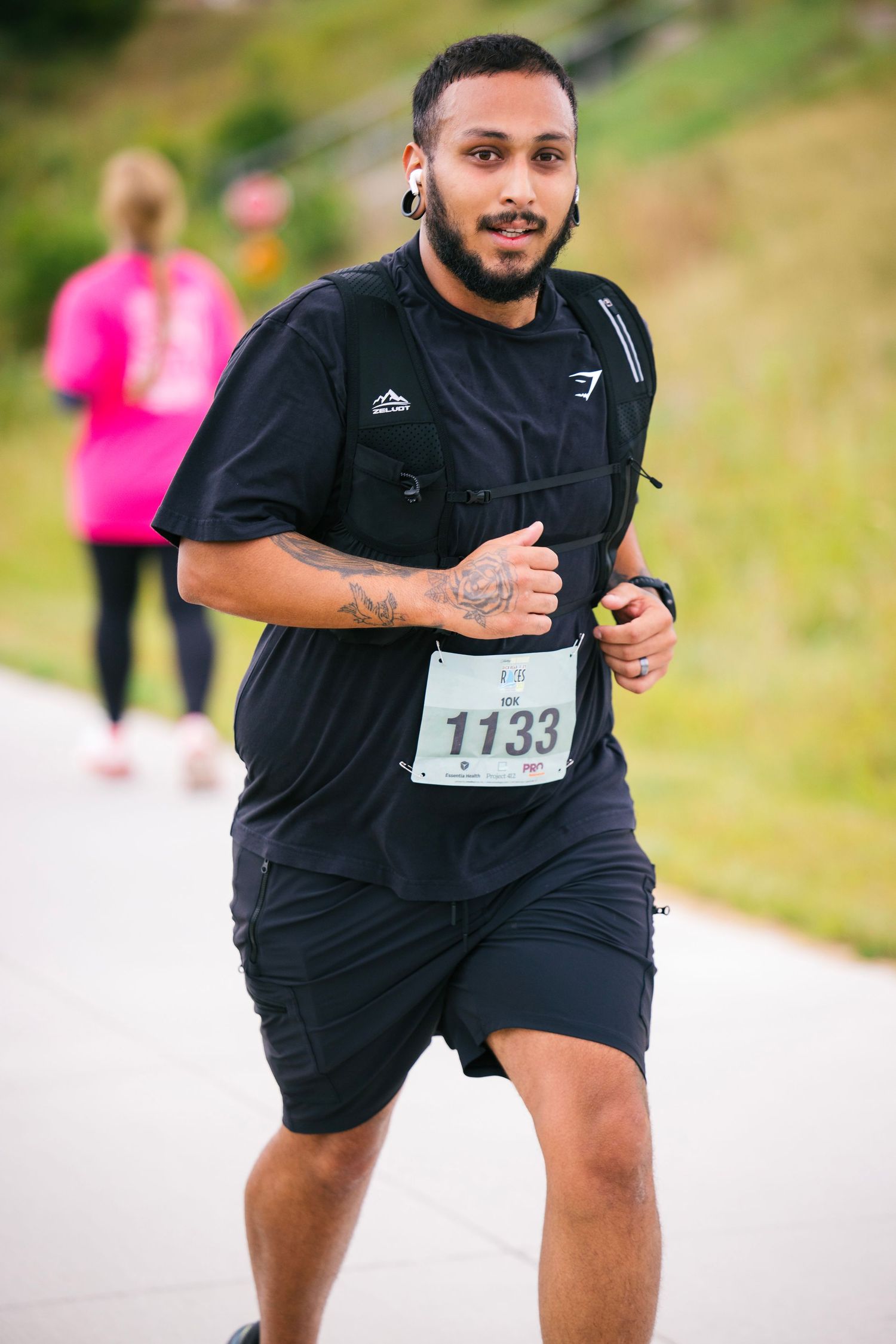 Runner in black athletic wear sprints energetically during outdoor race competition.