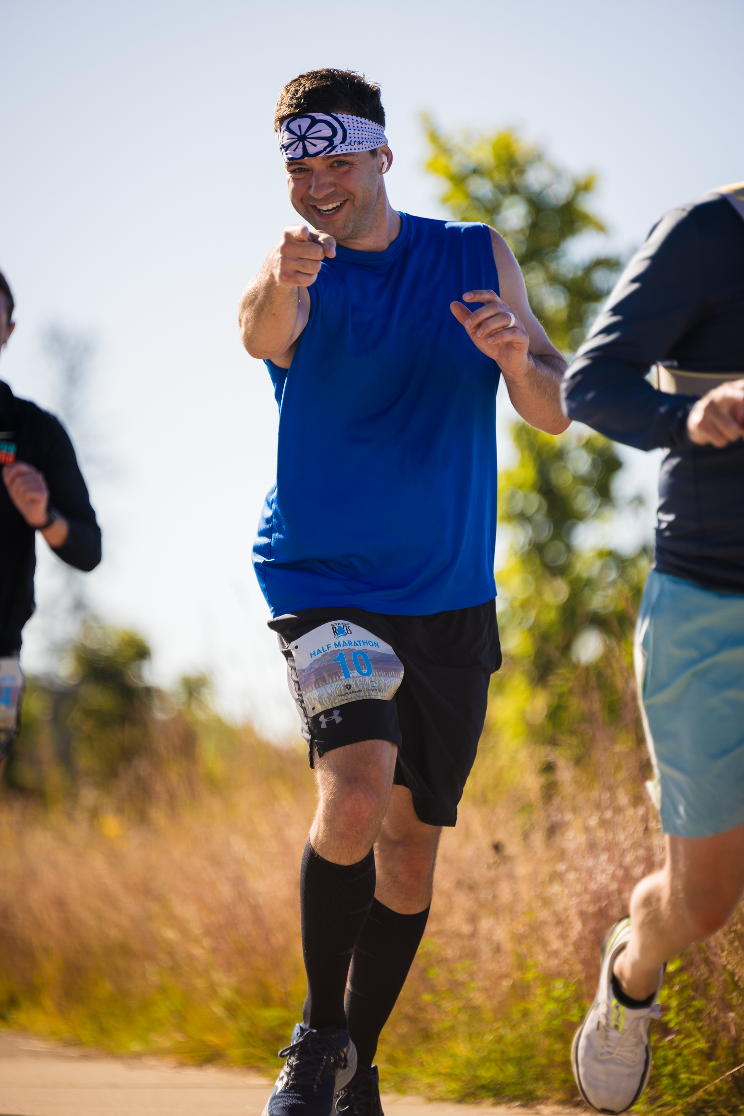 Runners' legs in athletic gear moving along a trail during an outdoor fitness activity.