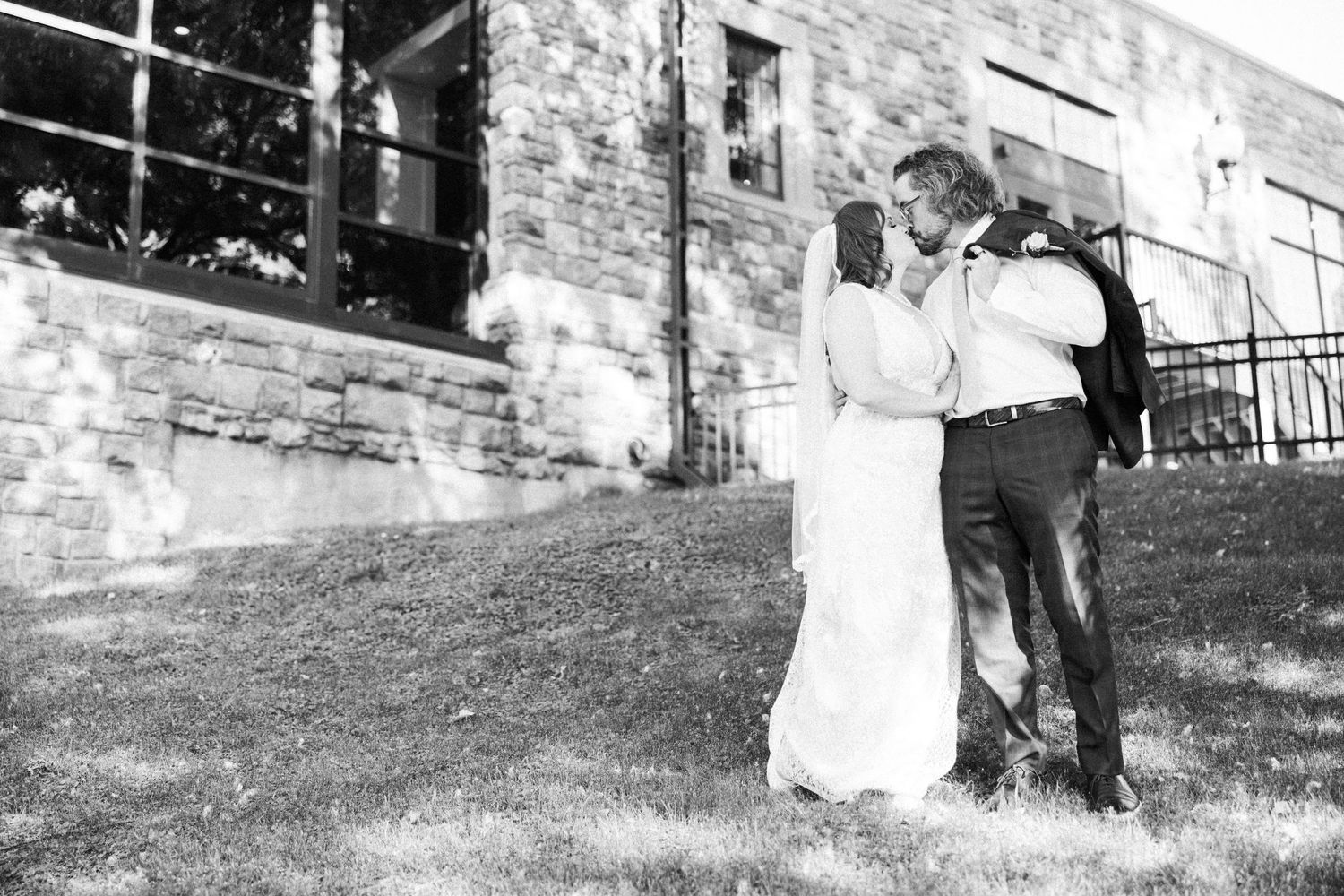Black and white series showing couple's romantic moments by stone wall.