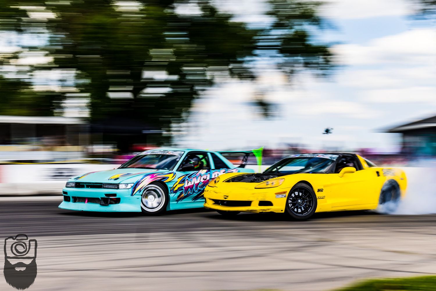 Colorful drift cars performing synchronized sliding maneuvers on a racing circuit.