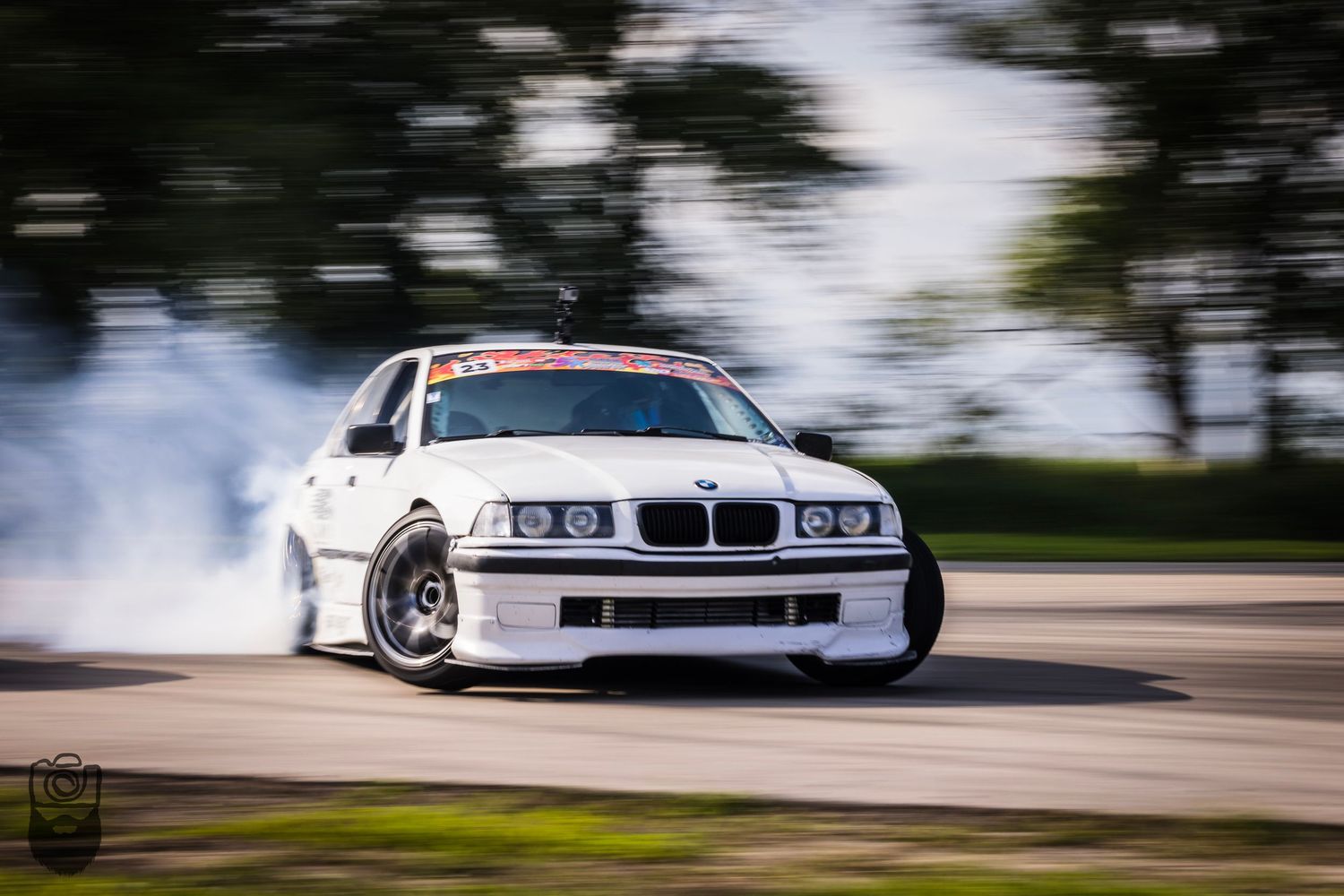 Light blue BMW performing a drift maneuver on track.
