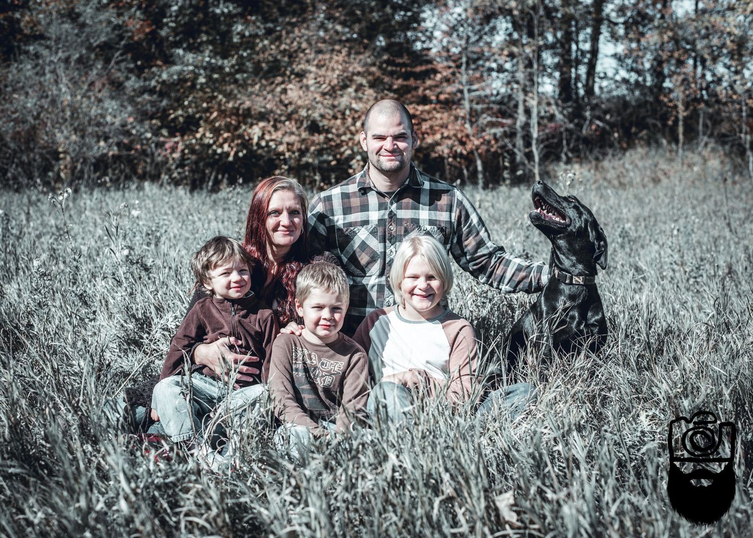 Family group photo session in tall grass with vintage filter effect.