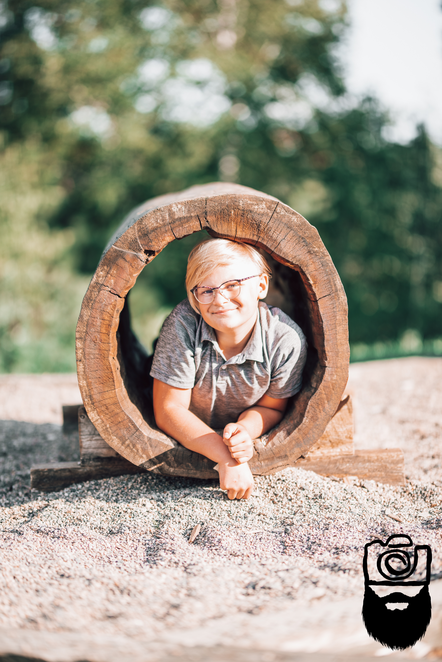 Creative portrait taken through a hollow log tunnel in a playground.