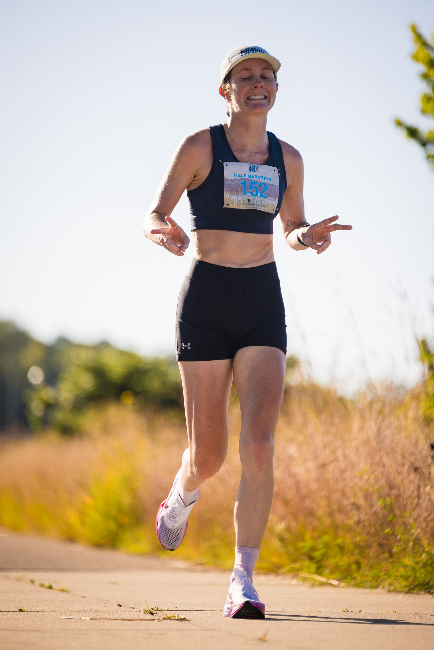 Close-up of runner's legs in black shorts and white shoes on a dirt path during a race.