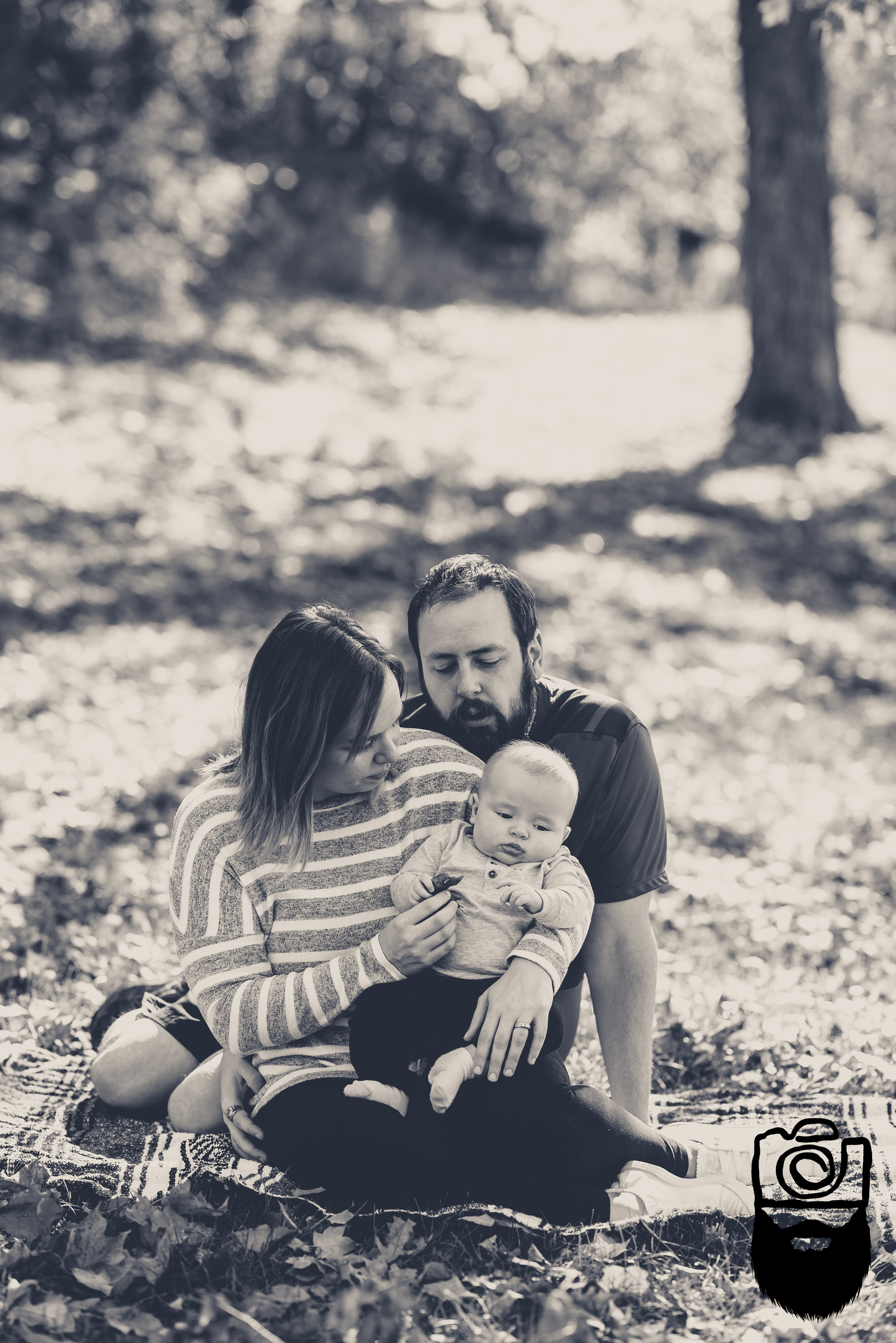 Family sitting together on ground in black and white portrait.