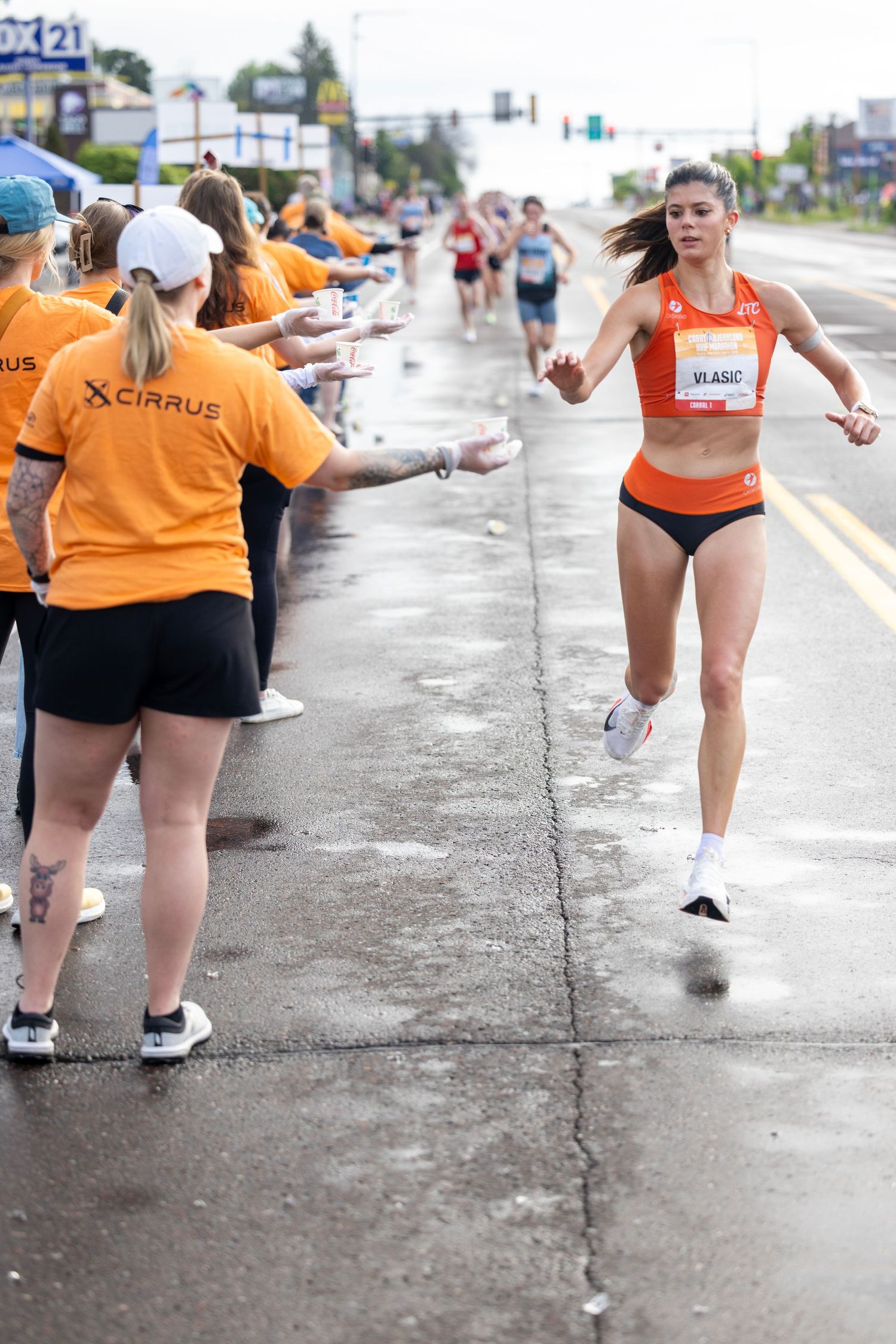 Group of participants in orange shirts cheering during a community event on a rainy day.