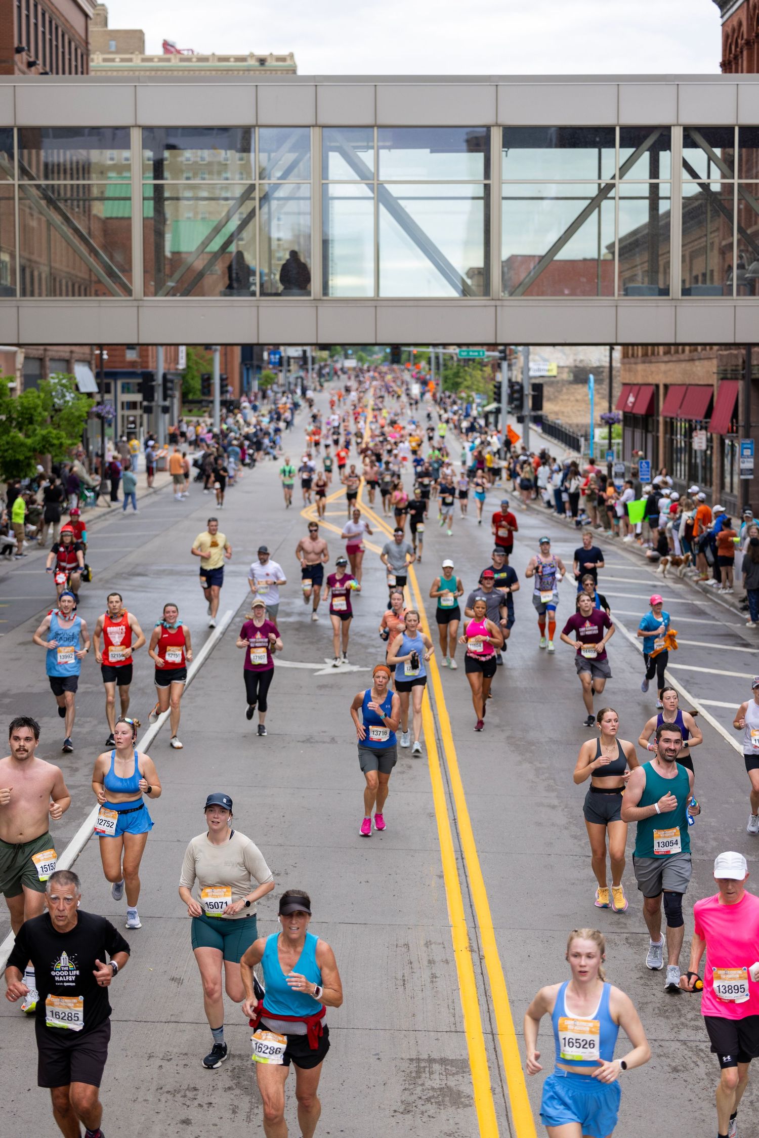 Large crowd of marathon runners racing down a wide city street.