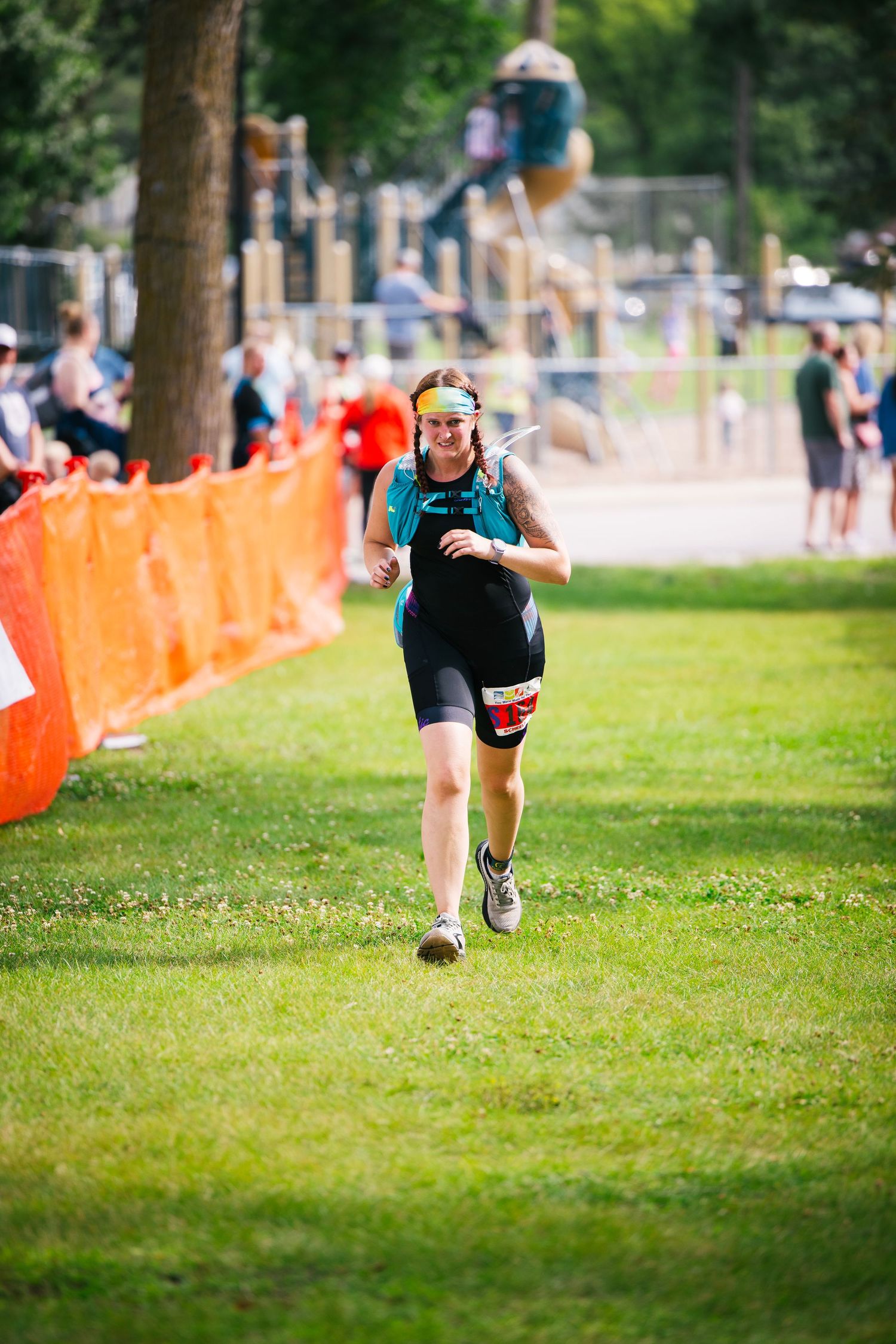 Runner sprinting across grassy field with orange barriers visible in background.