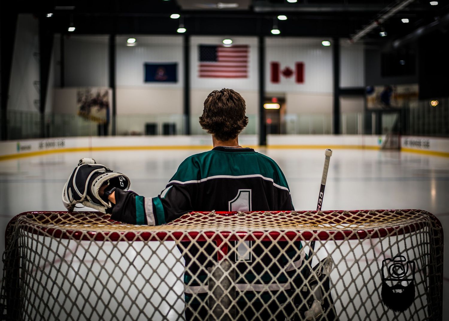Hockey arena interior showing spectator seating with American and Canadian flags.