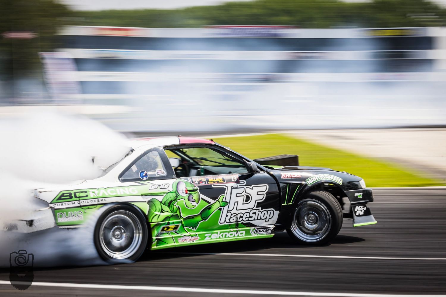 Professional drift cars sliding sideways on racetrack with motion blur effects.