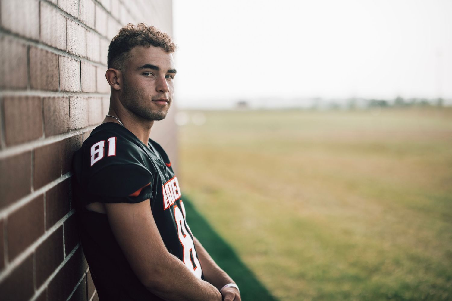 Athletic portrait series against white brick wall in outdoor setting.