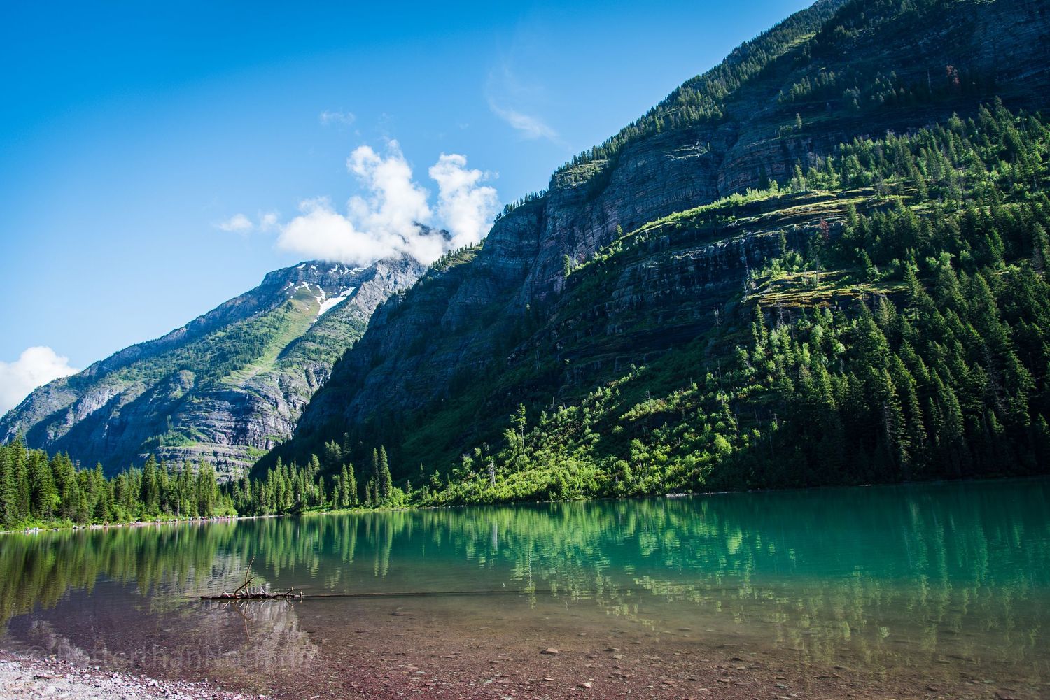 Scenic mountain lake with turquoise waters surrounded by towering peaks and evergreen forests.