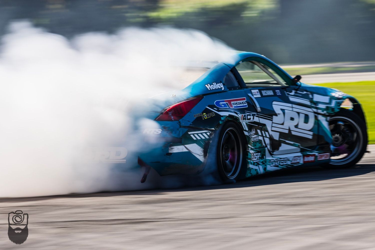Drifting race car creating smoke clouds while performing on a track.